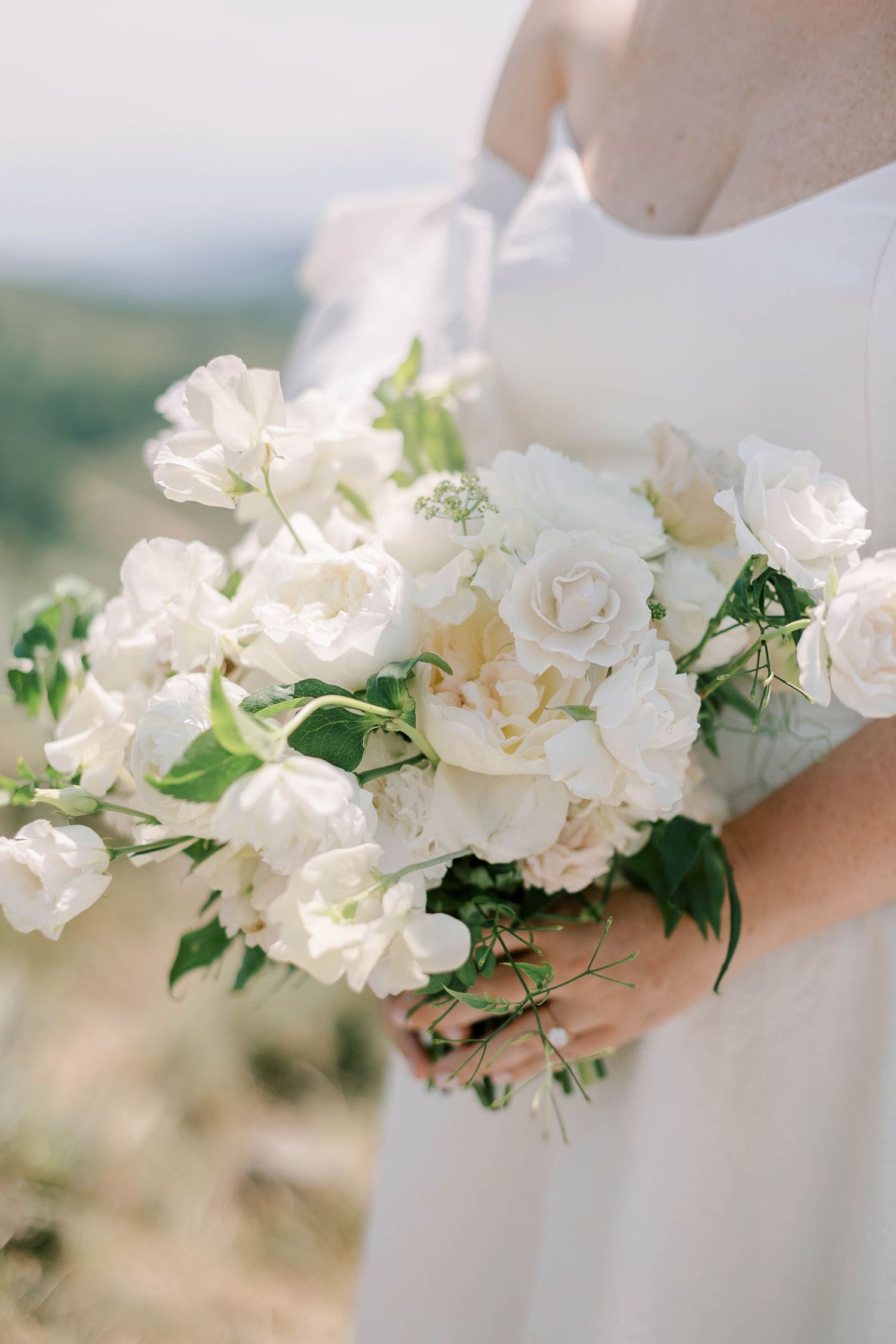Close-up of elegant white and cream bridal bouquet with roses and greenery.