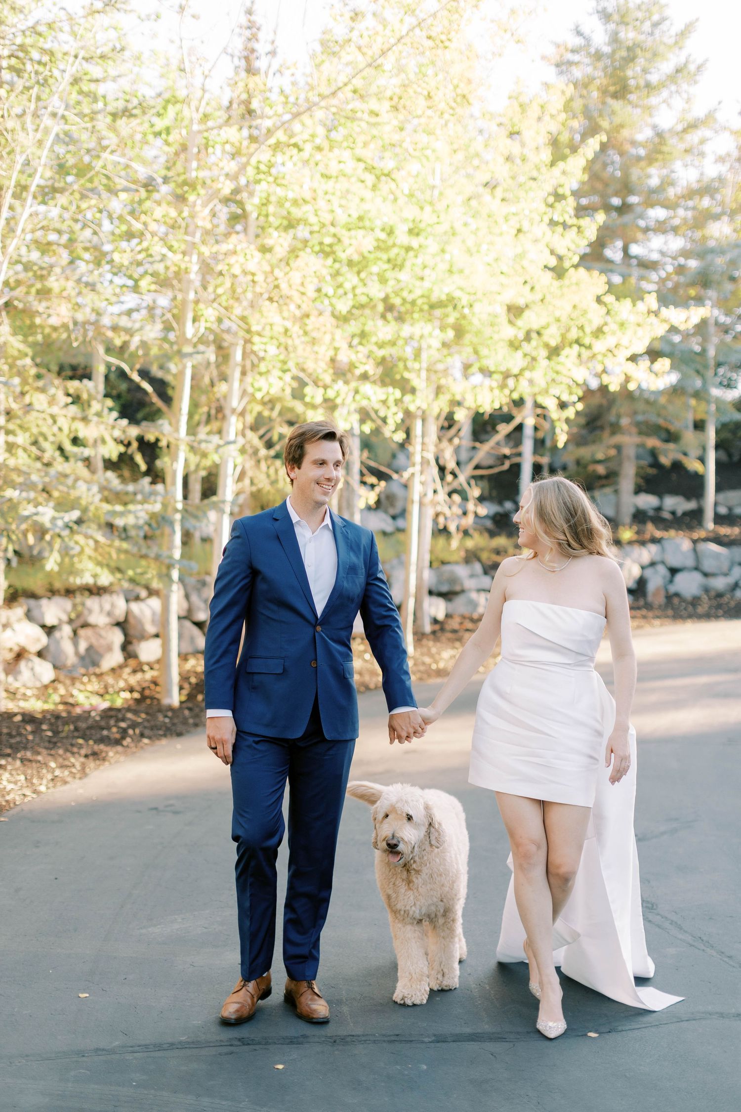 Couple walking their white dog on paved path with autumn trees in background at promontory park city.