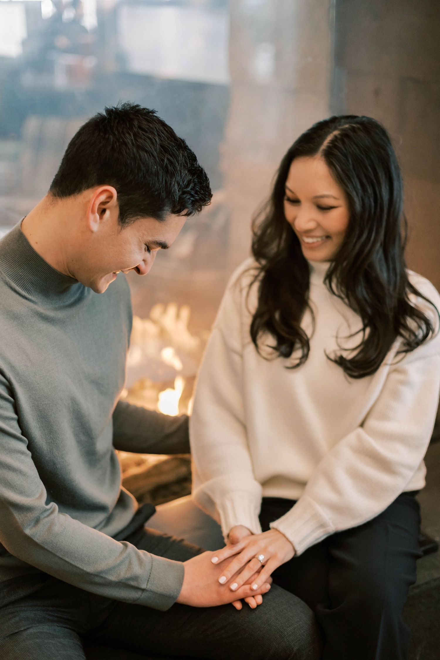 An intimate moment shared on a couch with warm firelight in the background at the Pendry park city.