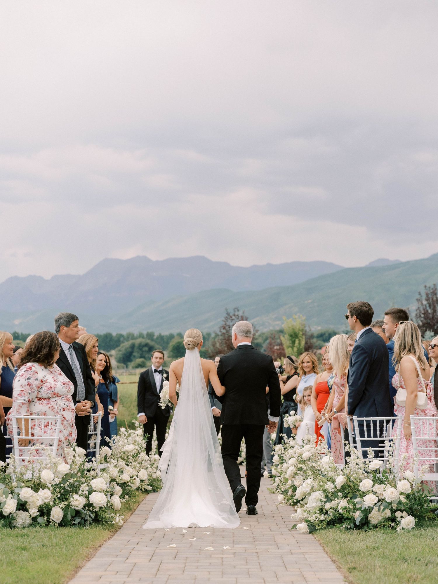 Elegant outdoor wedding ceremony with floral aisle decorations set against a backdrop of mountain views.