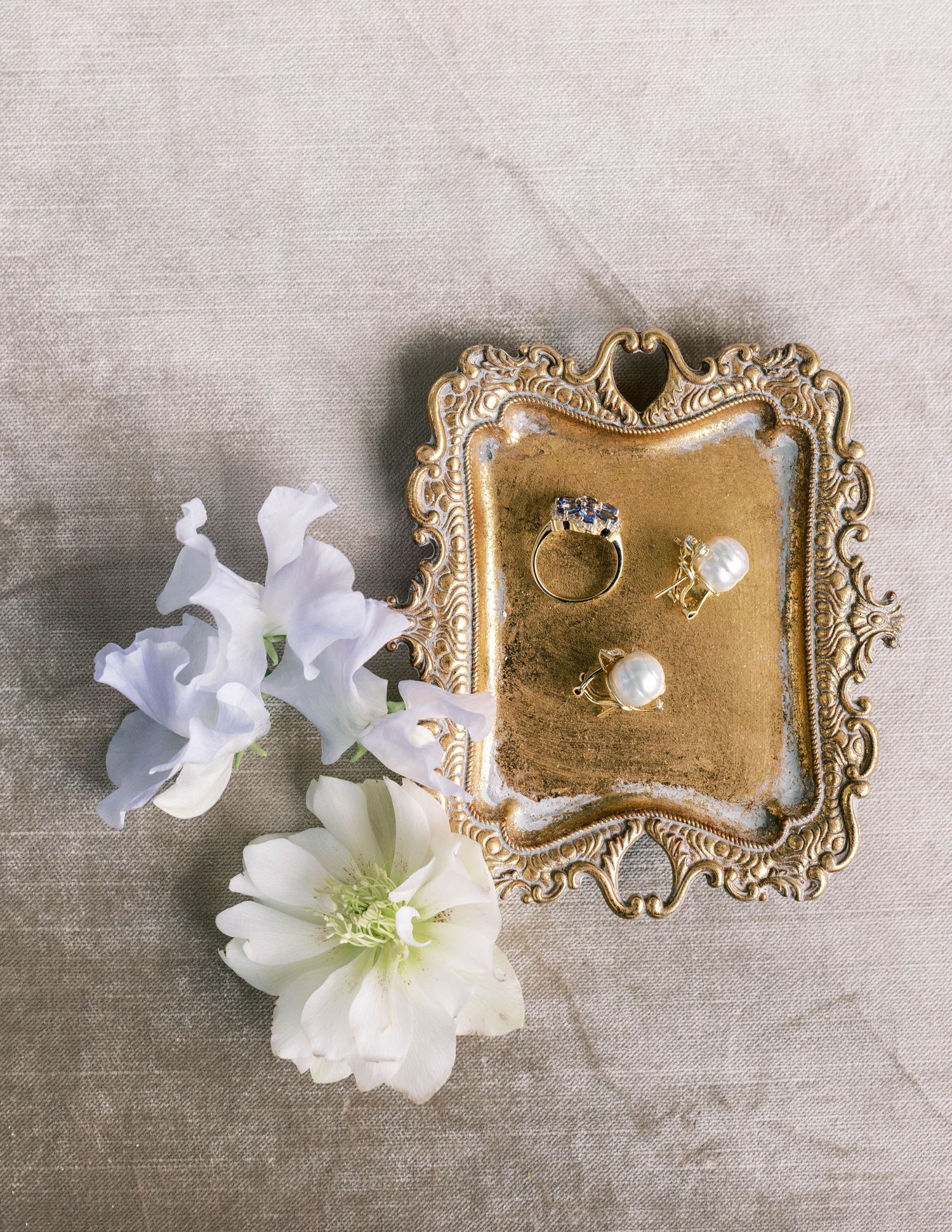 Wedding rings displayed on an ornate gold tray with white flowers for decoration.