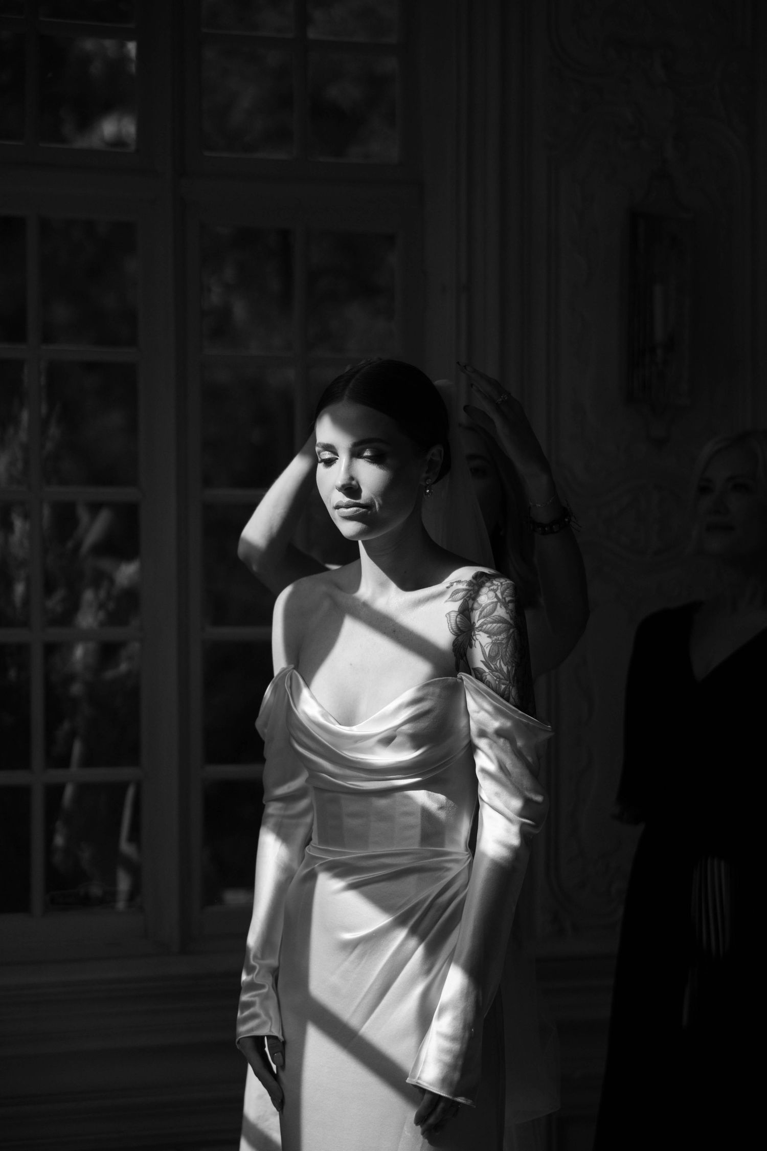 Dramatic black and white portrait of bride in silk dress by window.