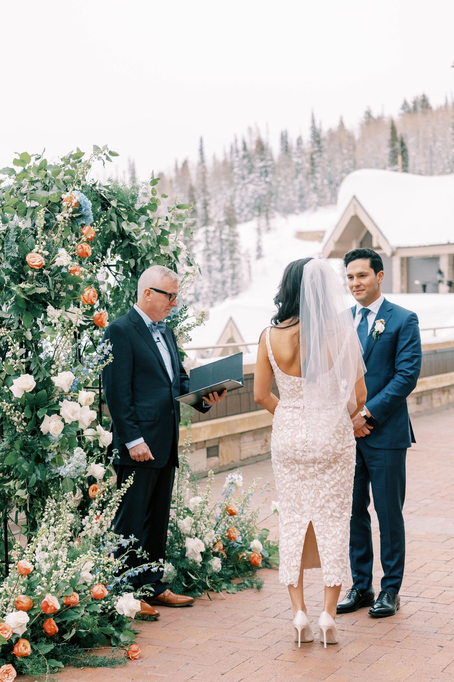 Wedding ceremony on a mountain terrace with floral arch and snow-capped peaks in background at the montage deer valley.