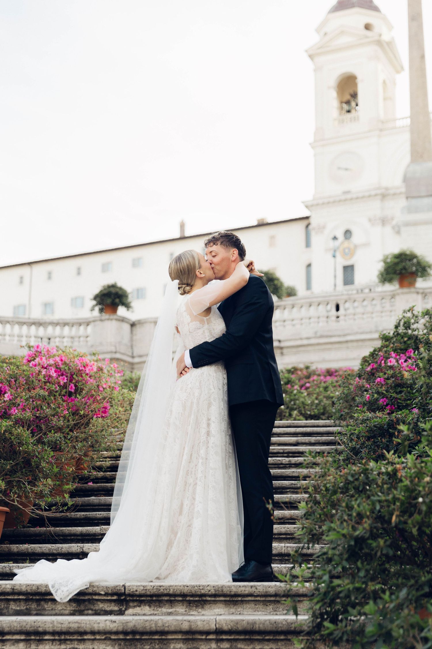 Romantic moment between newlyweds on steps of Spanish church with bell tower of rome italy