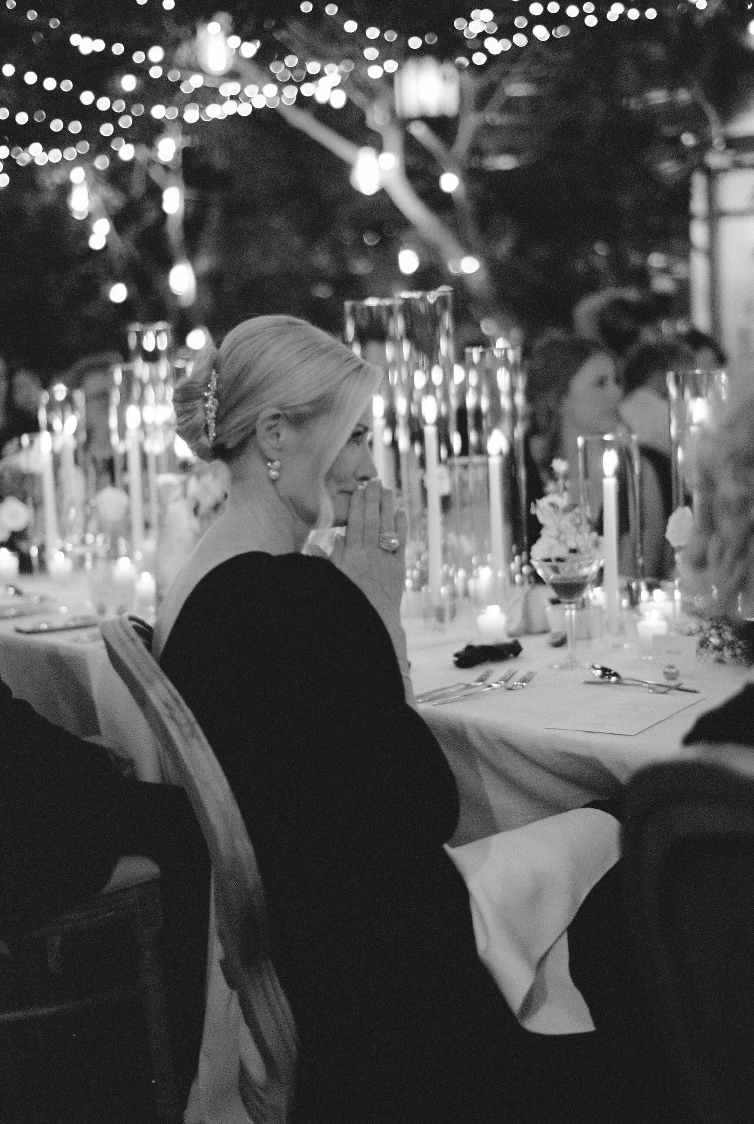 Elegant dinner table setting with string lights and candles creating a romantic atmosphere.