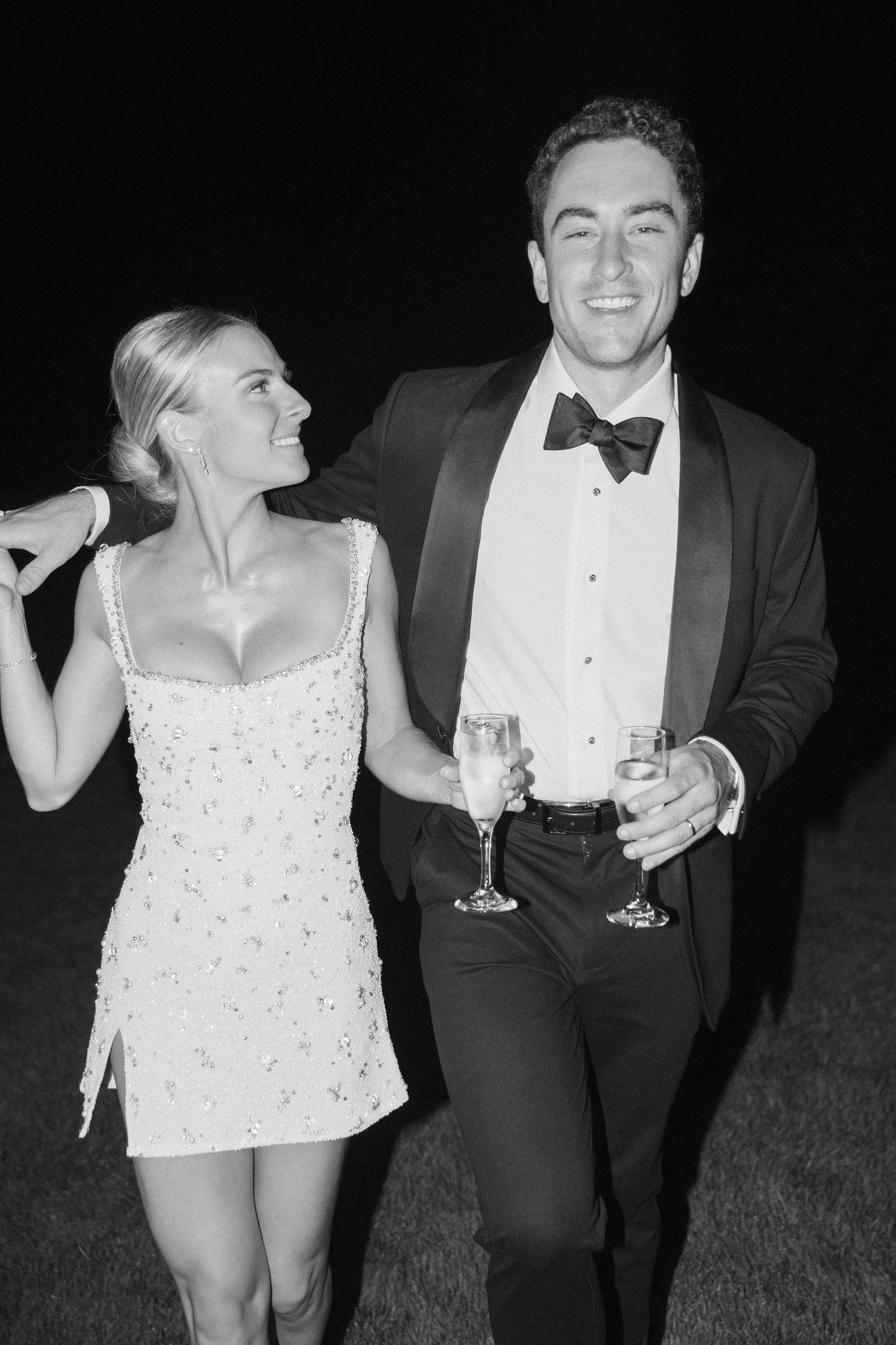 A couple in formal attire enjoying champagne during an evening celebration.