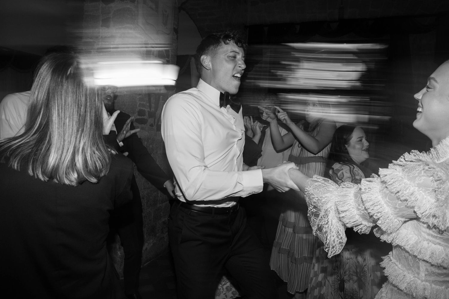 Black and white photo of lively dancing at an evening celebration.