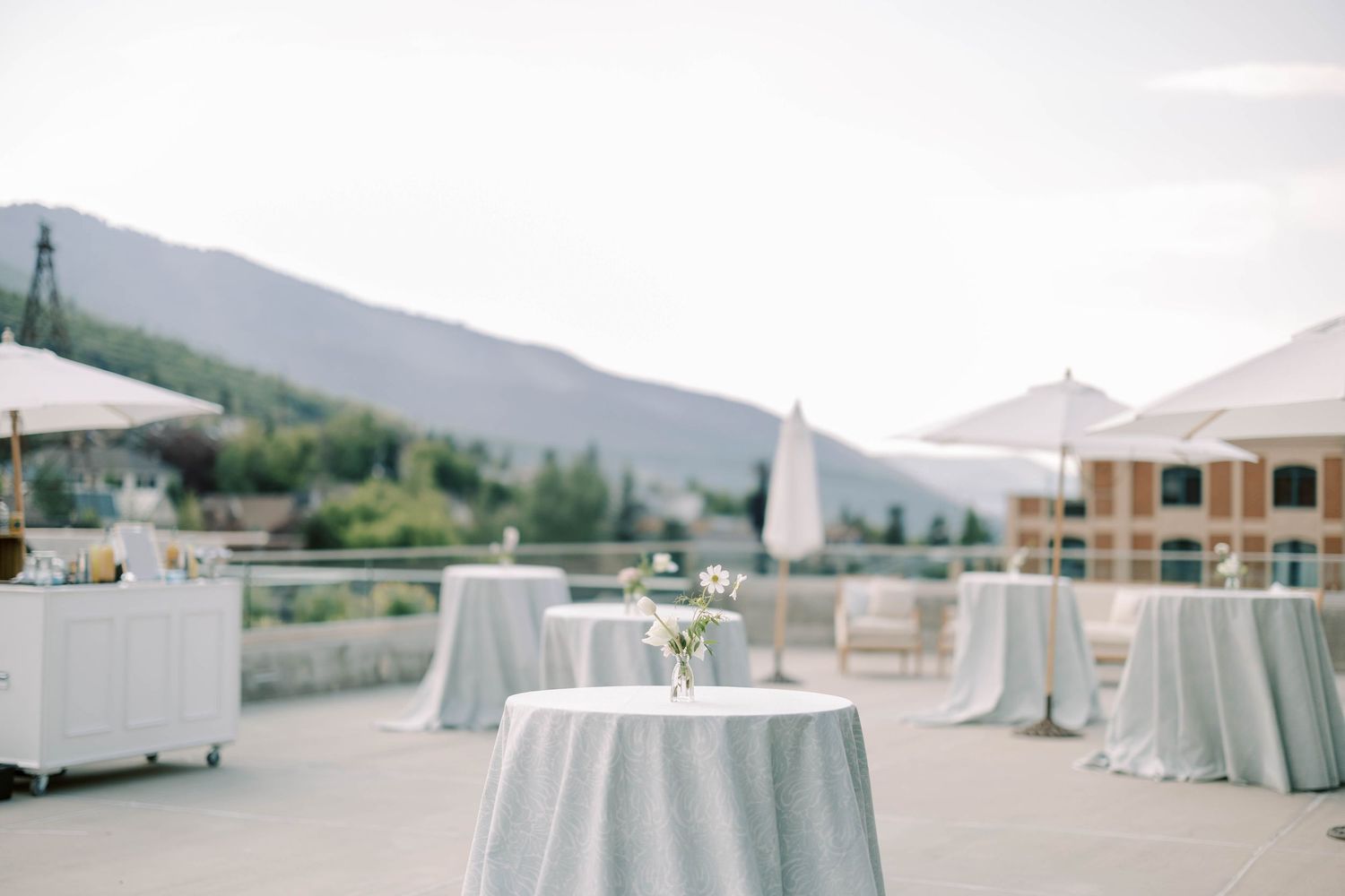Outdoor wedding reception setup with light blue tablecloths and mountain views.