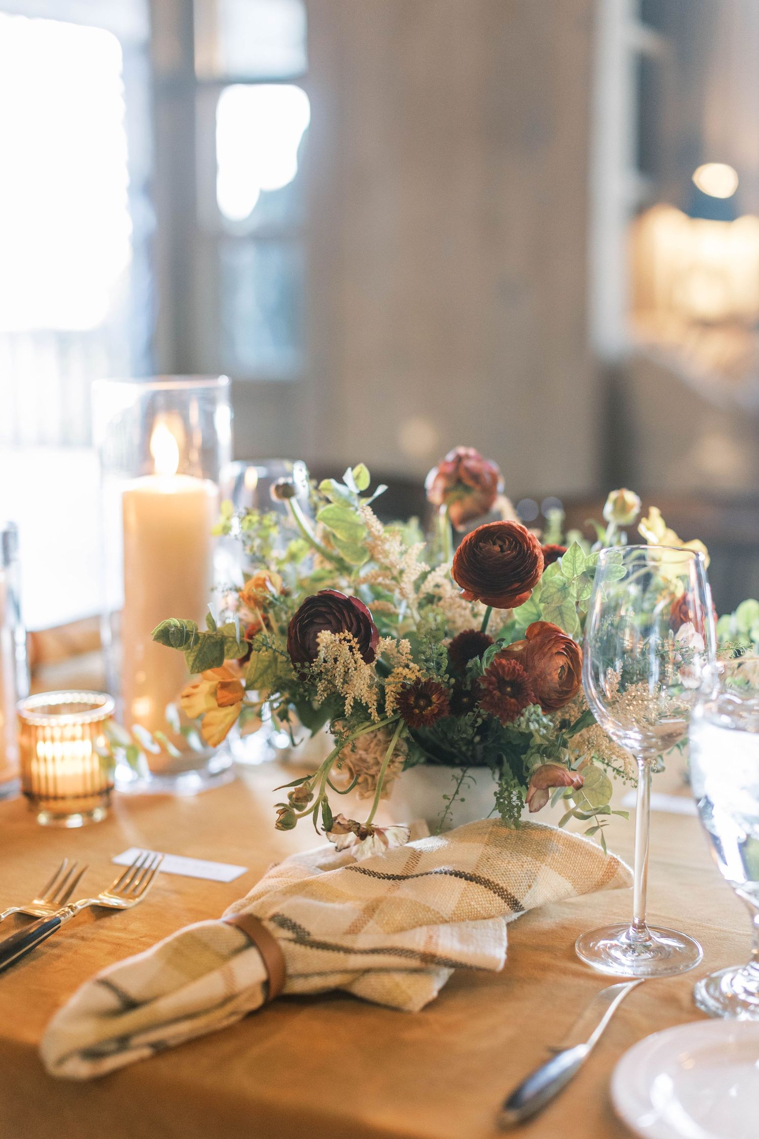 Sunlit table setting with rustic floral centerpiece and linen napkins at promontory park city.