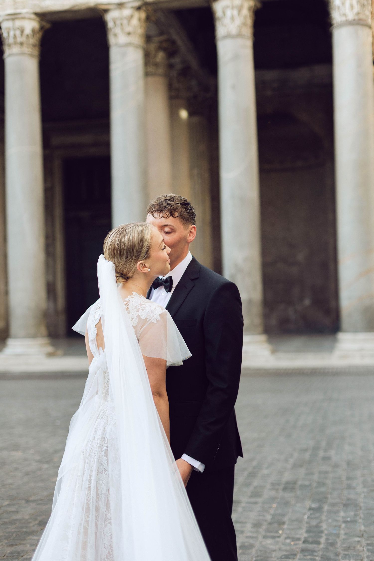 A romantic wedding moment captured in front of classical Italian architecture of the pantheon.