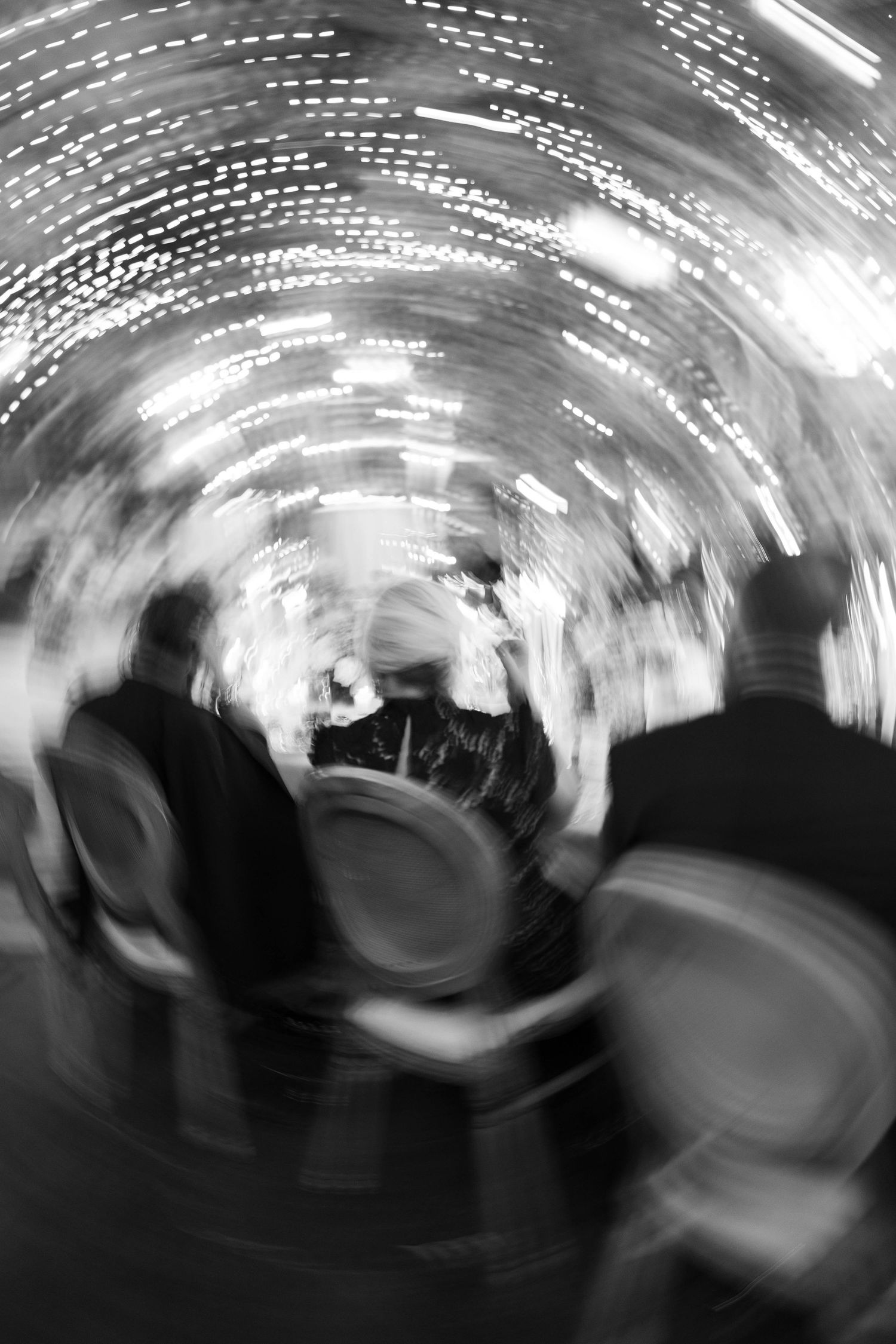 Abstract black and white motion blur of guests at an evening event with tunnel lighting effect.