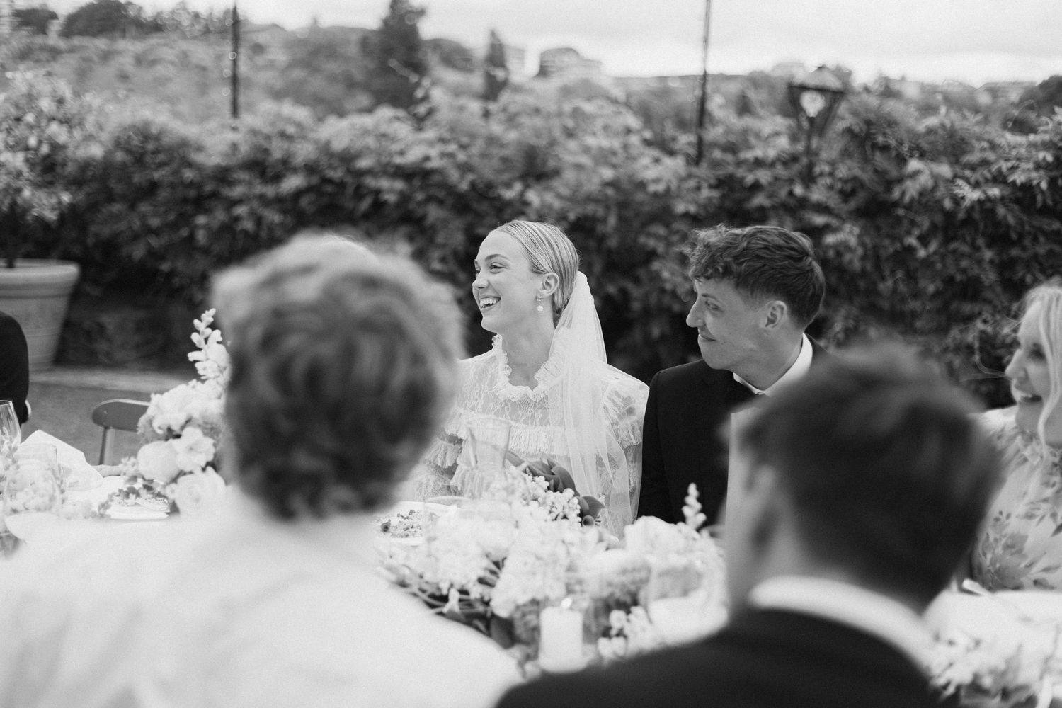 Black and white image of wedding reception guests dining outdoors.