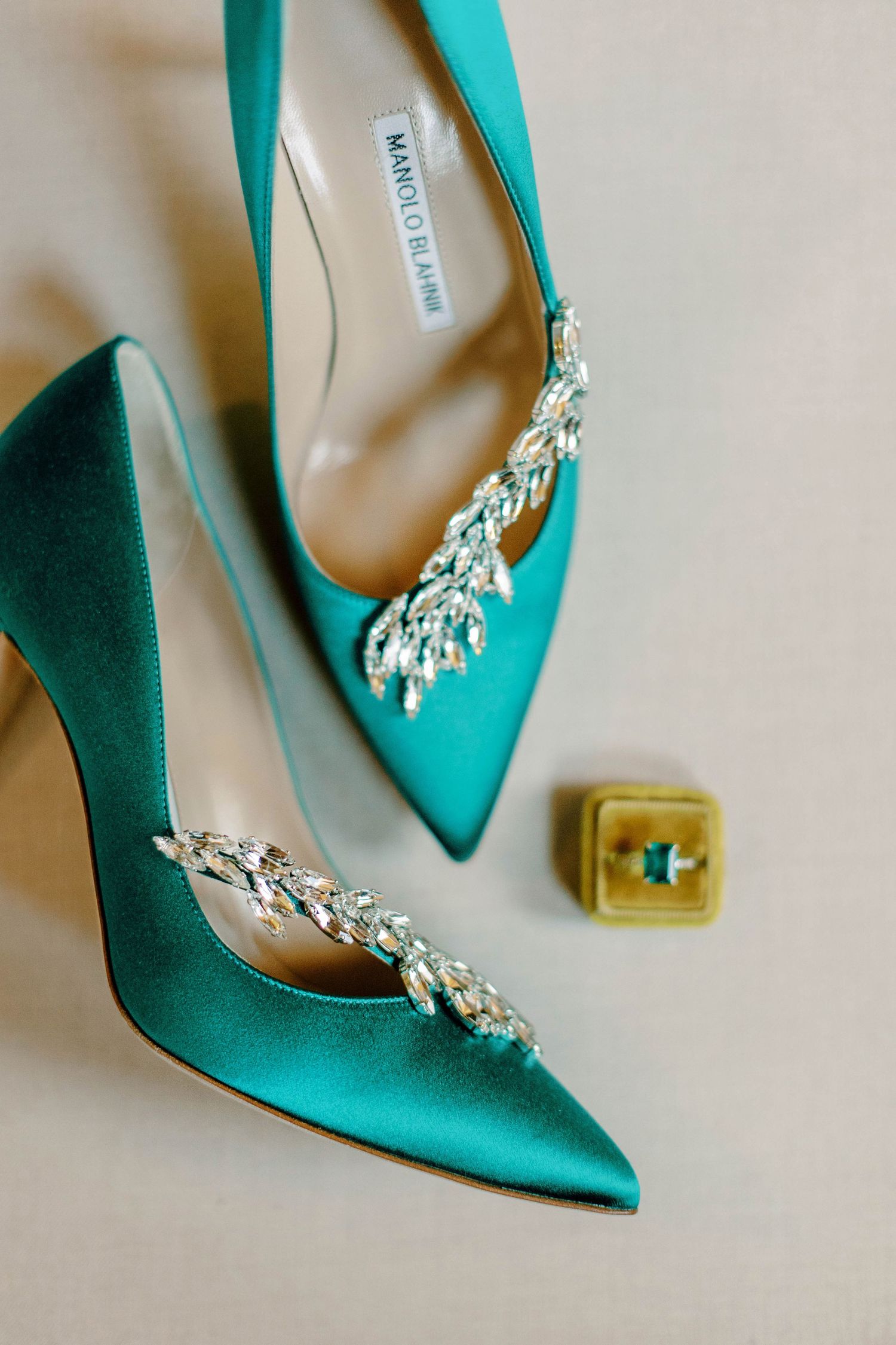 Teal satin wedding shoes with crystal embellishments next to vintage ring box.