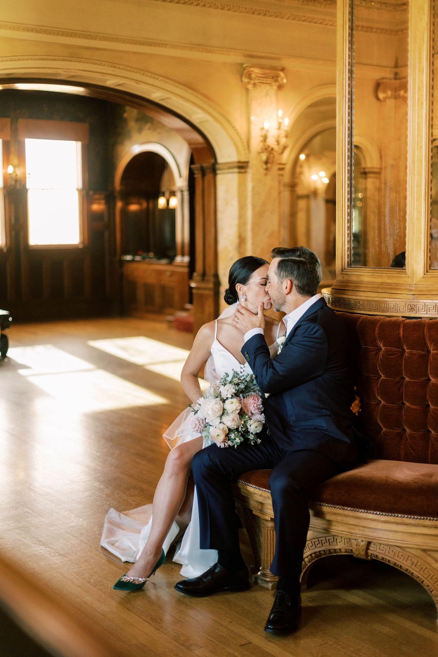 Couple sharing romantic moment on vintage bench in ornate room with arched doorways and wall sconces at the mccune mansion.