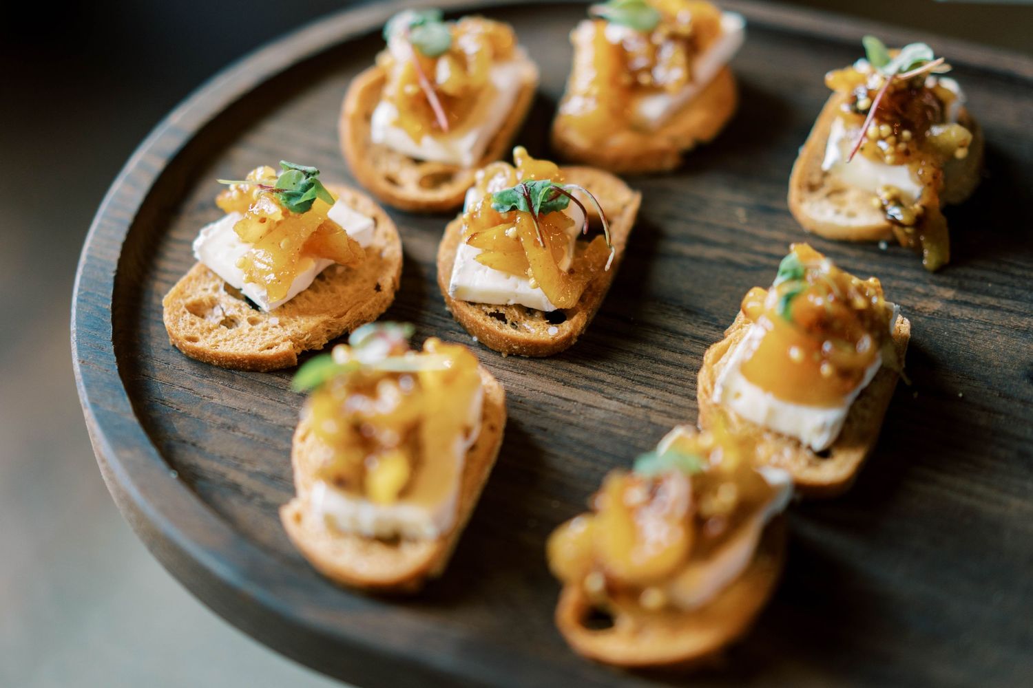Gourmet appetizers served on a wooden platter featuring bite-sized seafood canapés.