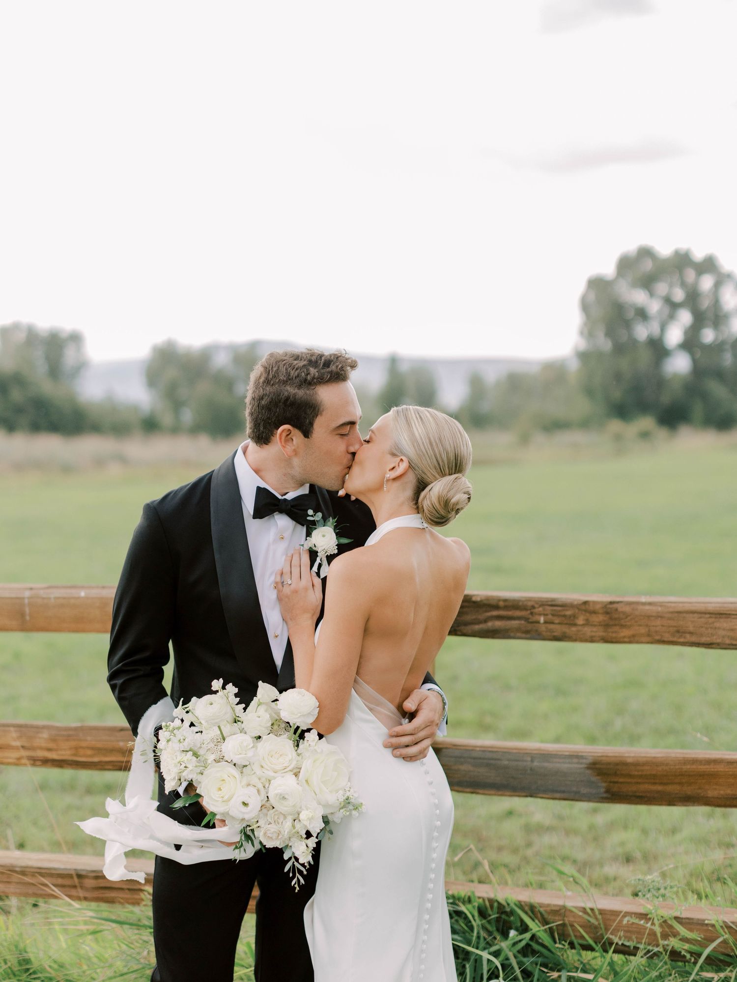 Romantic wedding moment by rustic wooden fence with white bouquet.