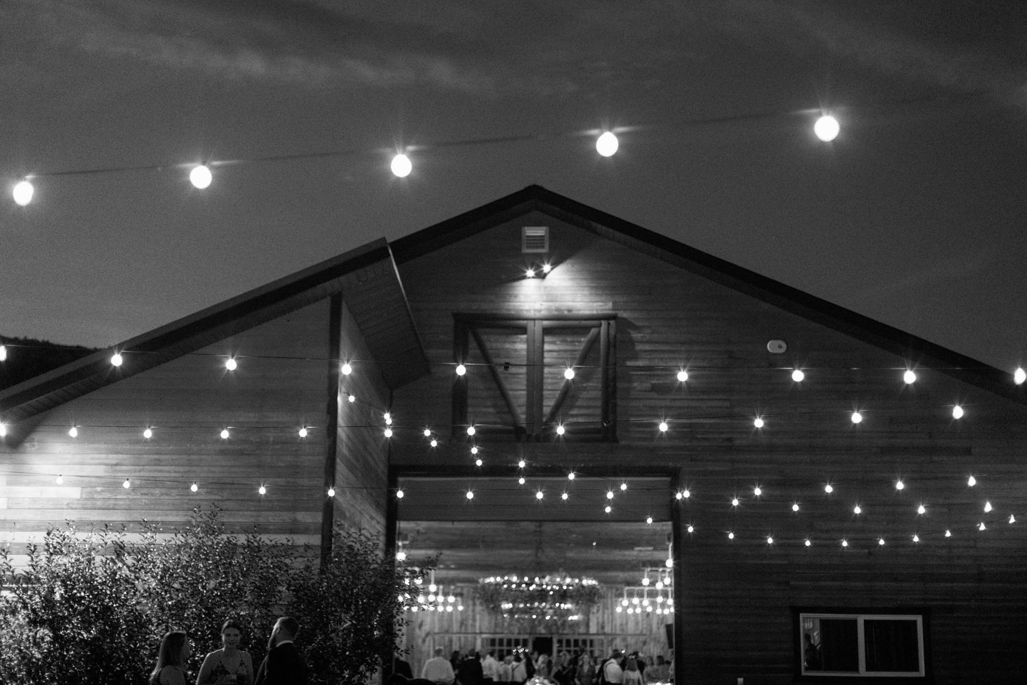 Rustic Blue Sky barn venue illuminated with string lights at night.