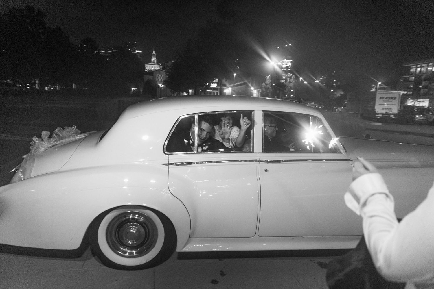 Classic car departure scene from a wedding celebration at night.