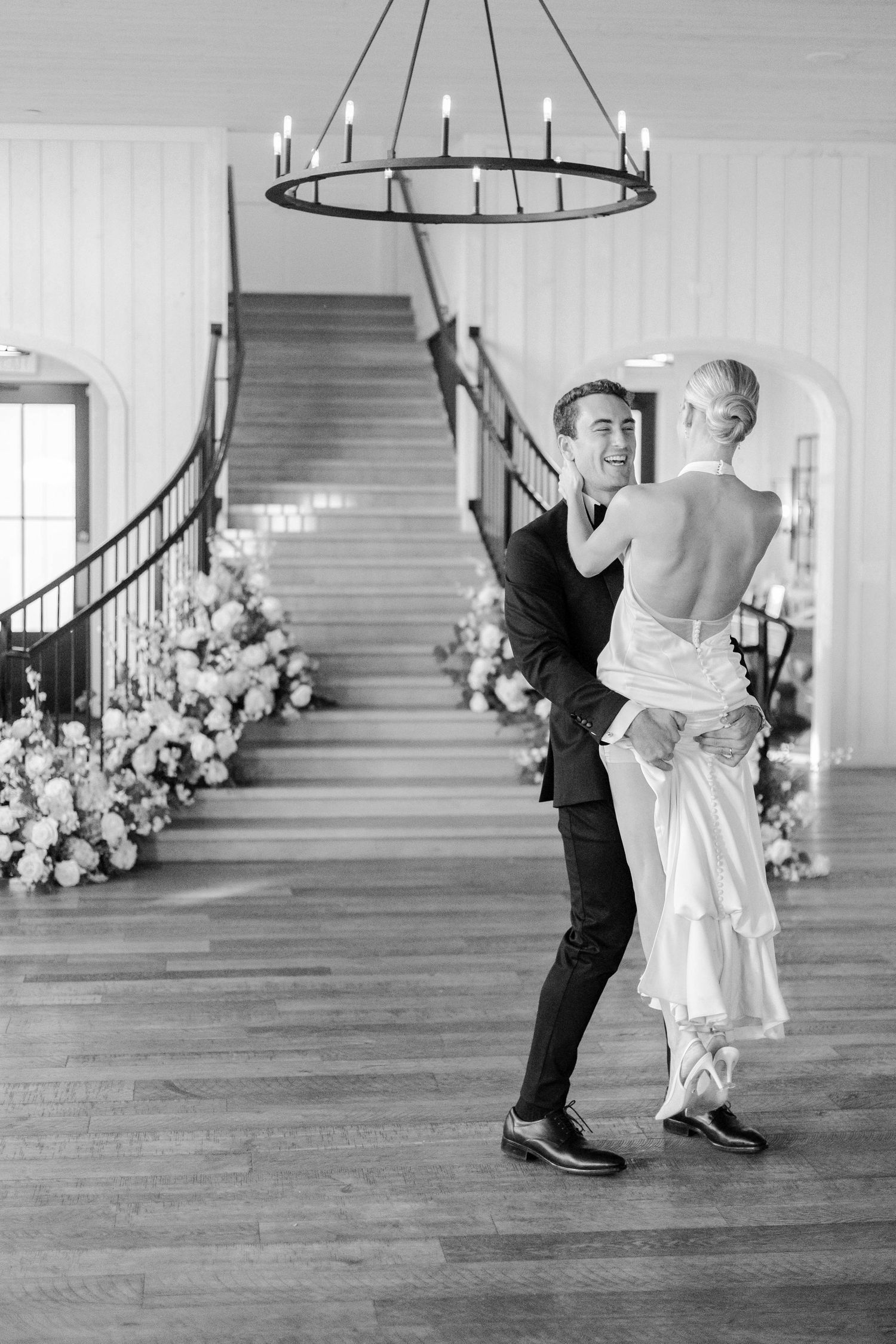 A couple dancing in black and white photography with a grand staircase in the background.