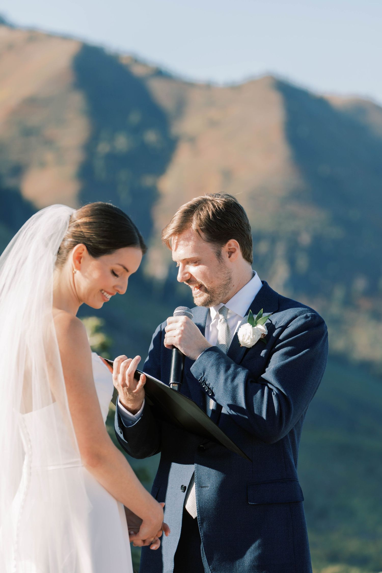 A wedding couple shares an intimate moment against a mountain backdrop during their ceremony.