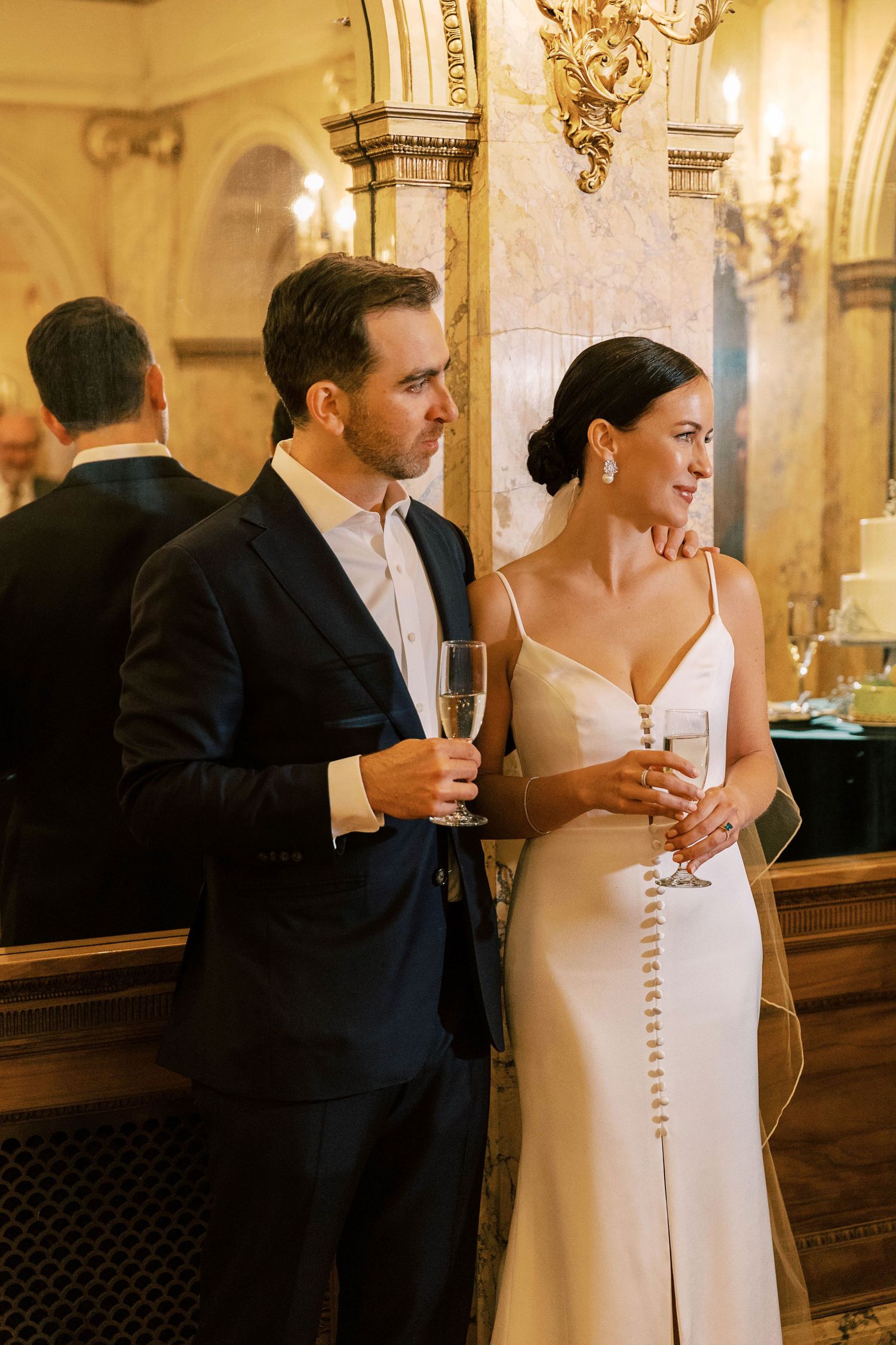 A couple shares an intimate moment at an elegant reception while holding champagne glasses.