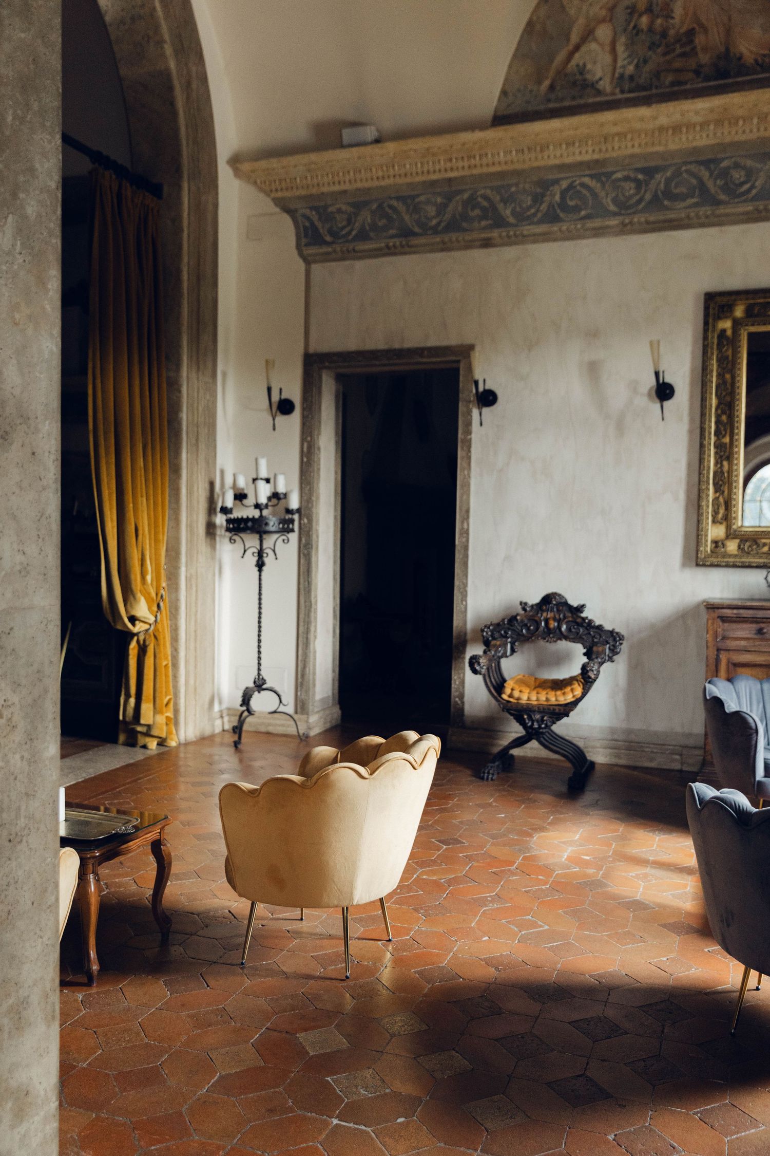 Elegant vintage interior with cream armchair and hexagonal terracotta floor tiles.