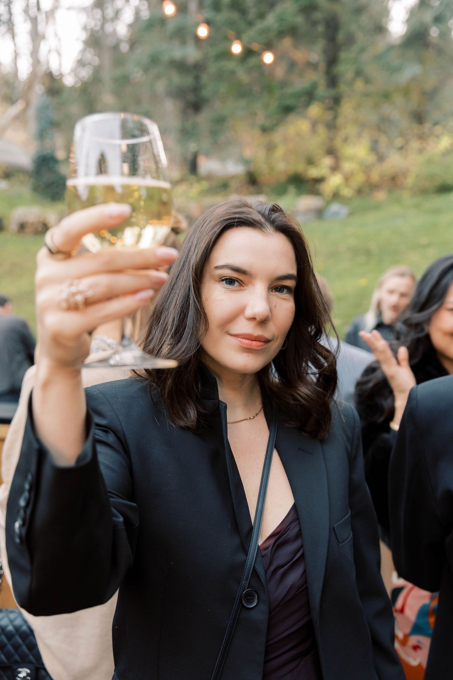 A guest raises a champagne glass in celebration at an outdoor event.