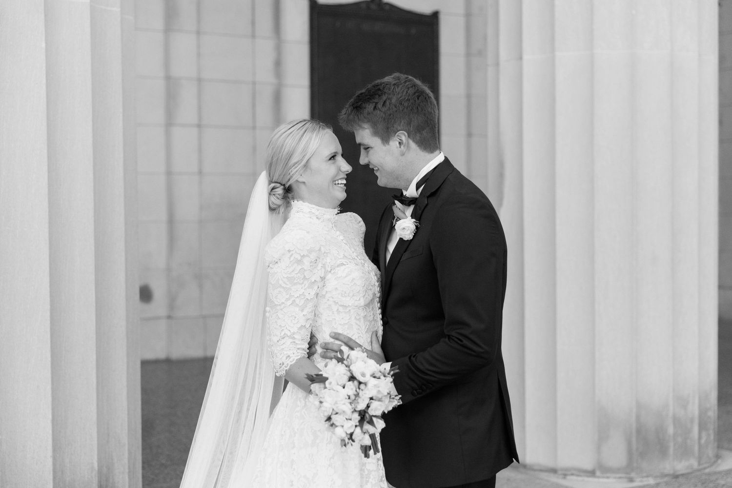 Romantic black and white wedding portrait against classical architecture.