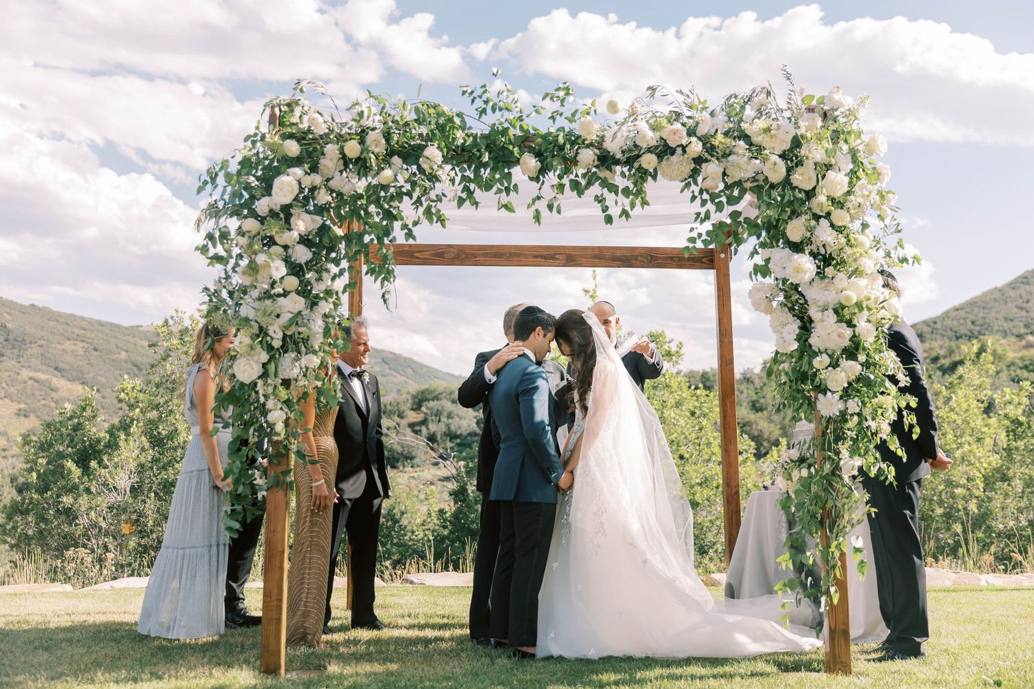 Floral-adorned wooden wedding arch with mountain views in the background.
