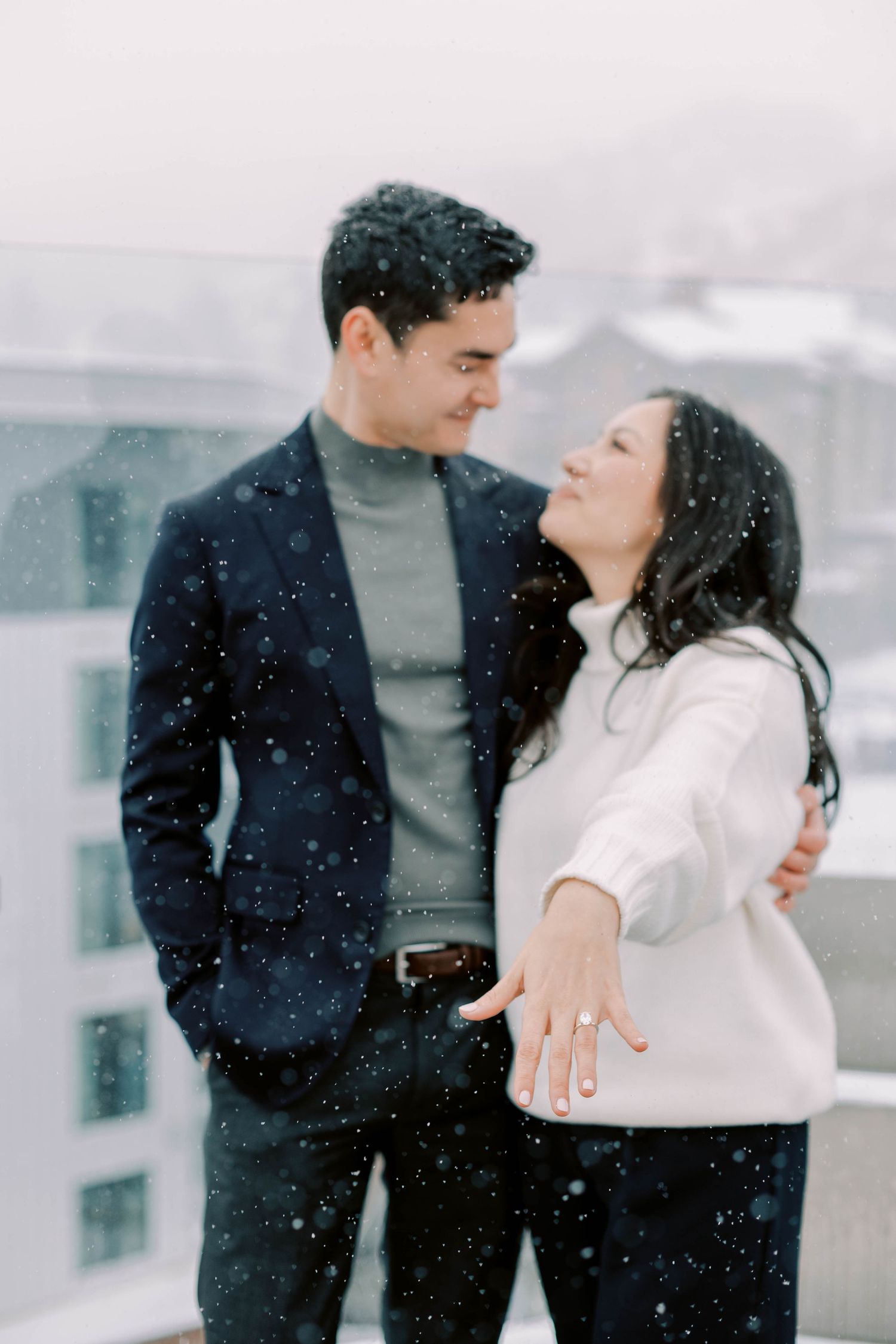 Couple in winter attire showing off engagement ring in snow after propsal at pendry in park city.