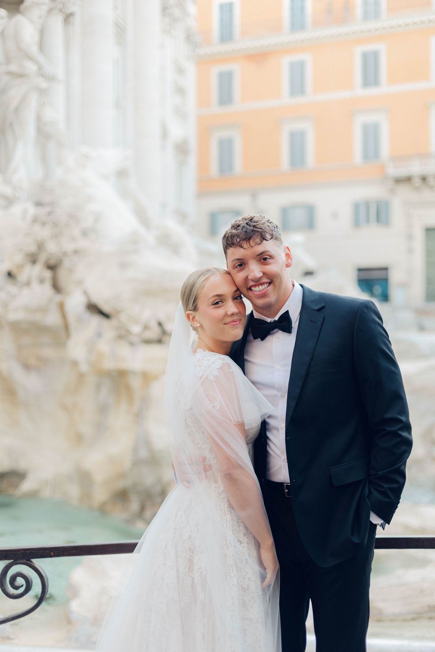 Joyful wedding portrait against the iconic backdrop of Rome's Trevi Fountain.
