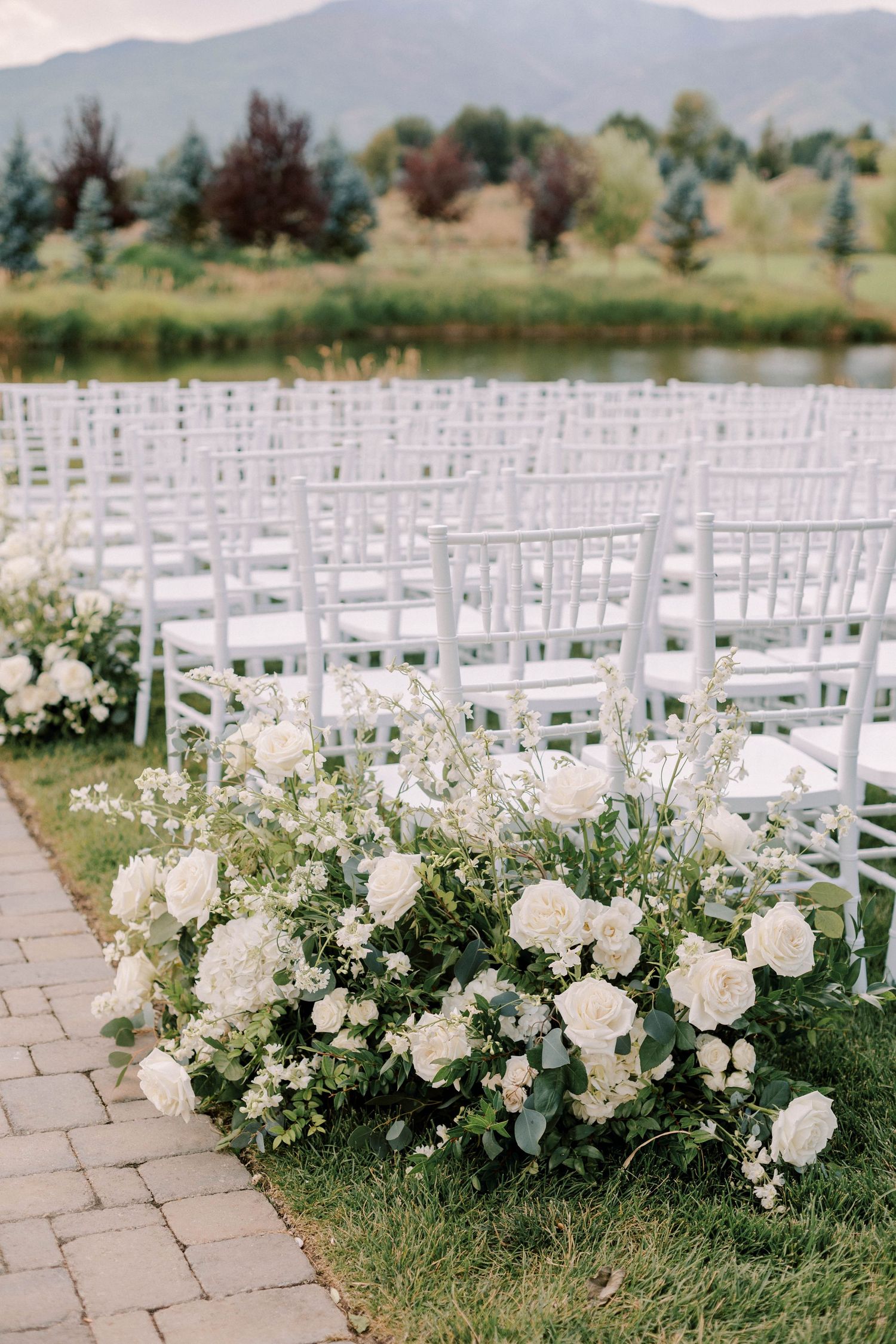 White garden chairs and floral aisle decorations at mountain wedding venue.