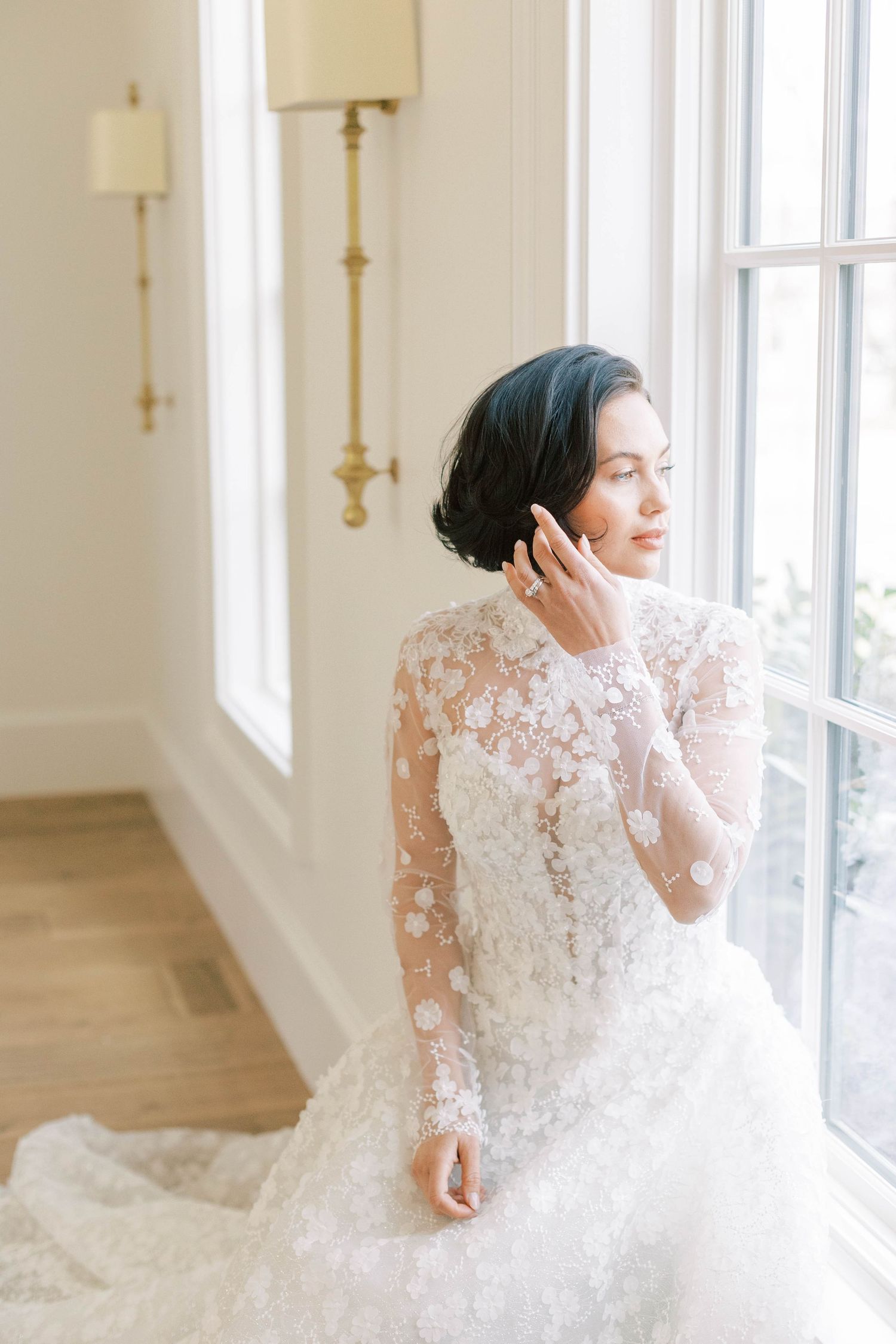 A delicate long-sleeve lace wedding dress captured in a sunlit room.