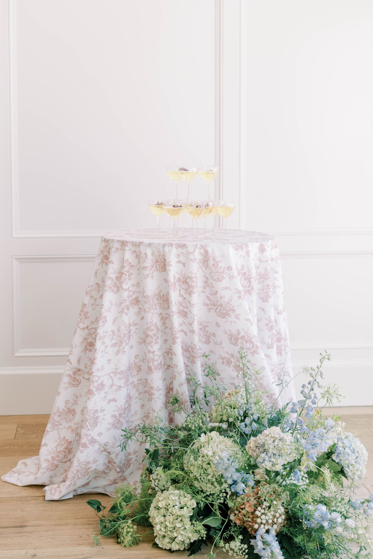 Elegant round table with floral pattern tablecloth and hydrangea arrangement.