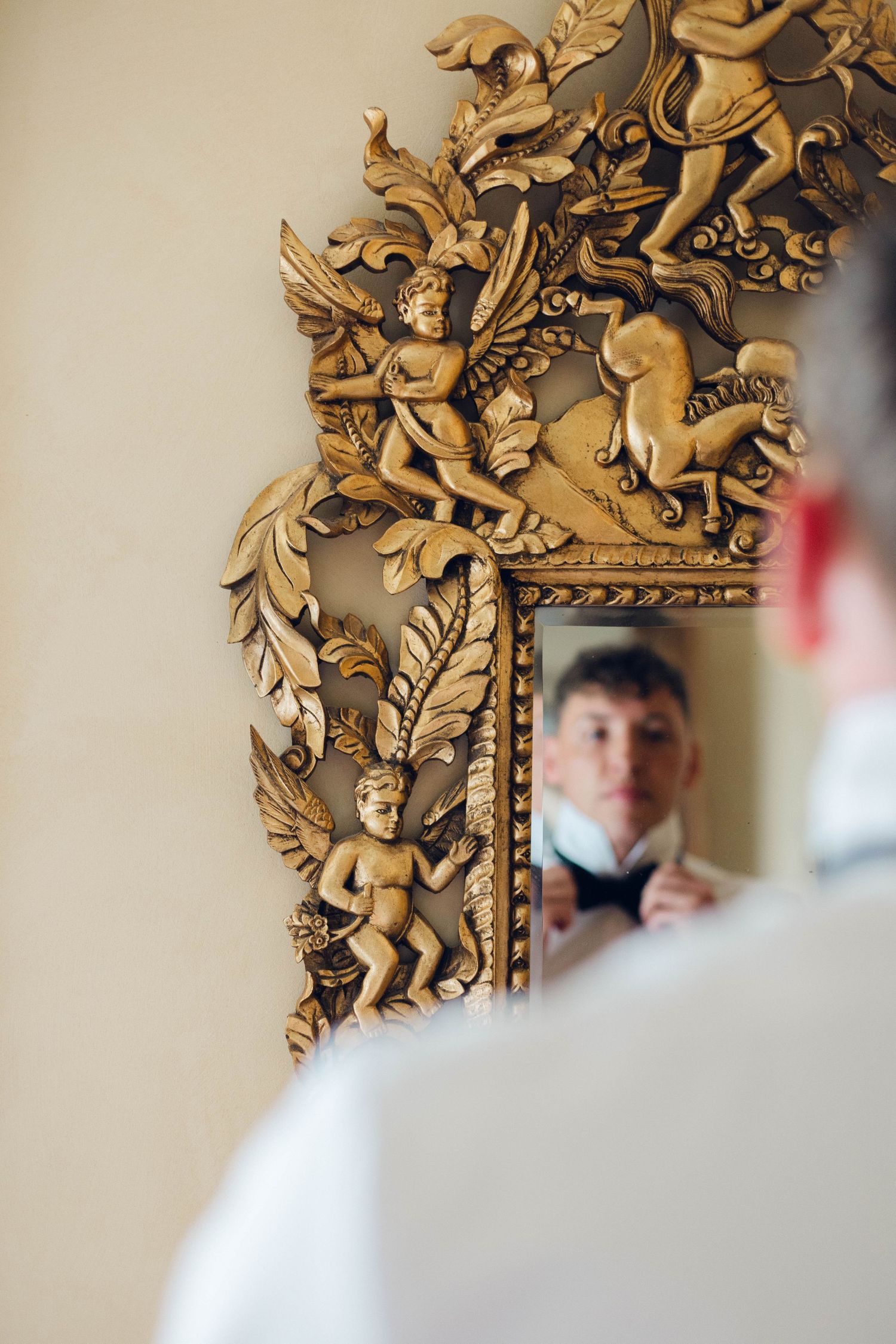Ornate gold baroque mirror frame with cherub and floral decorative details.