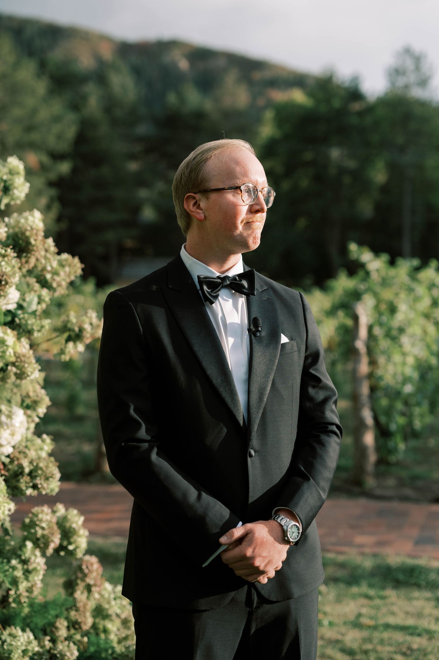 Formal portrait in vineyard setting with mountain backdrop during golden hour.
