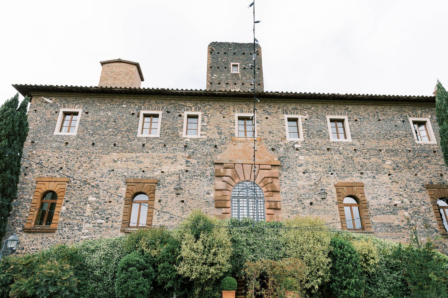 Historic stone villa with arched windows and rustic facade surrounded by greenery of castello della castellucia rome italy.