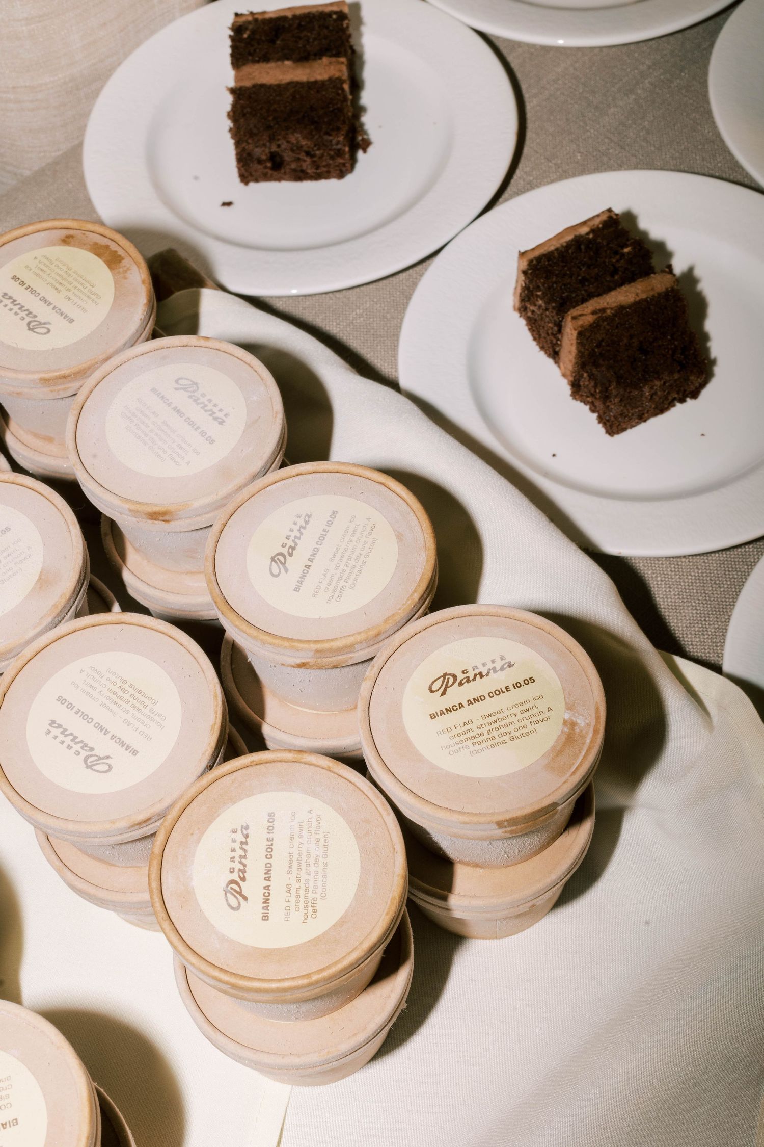 Slices of chocolate cake and stacked favor containers displayed at a wedding reception.
