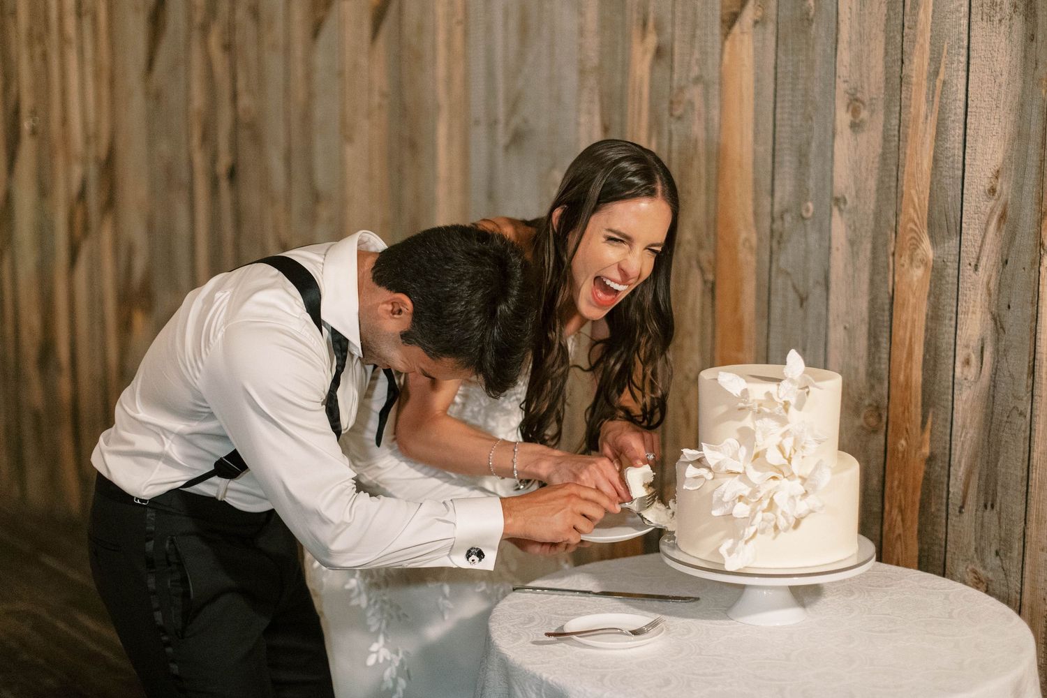 Couple cutting their elegant white wedding cake together at reception.