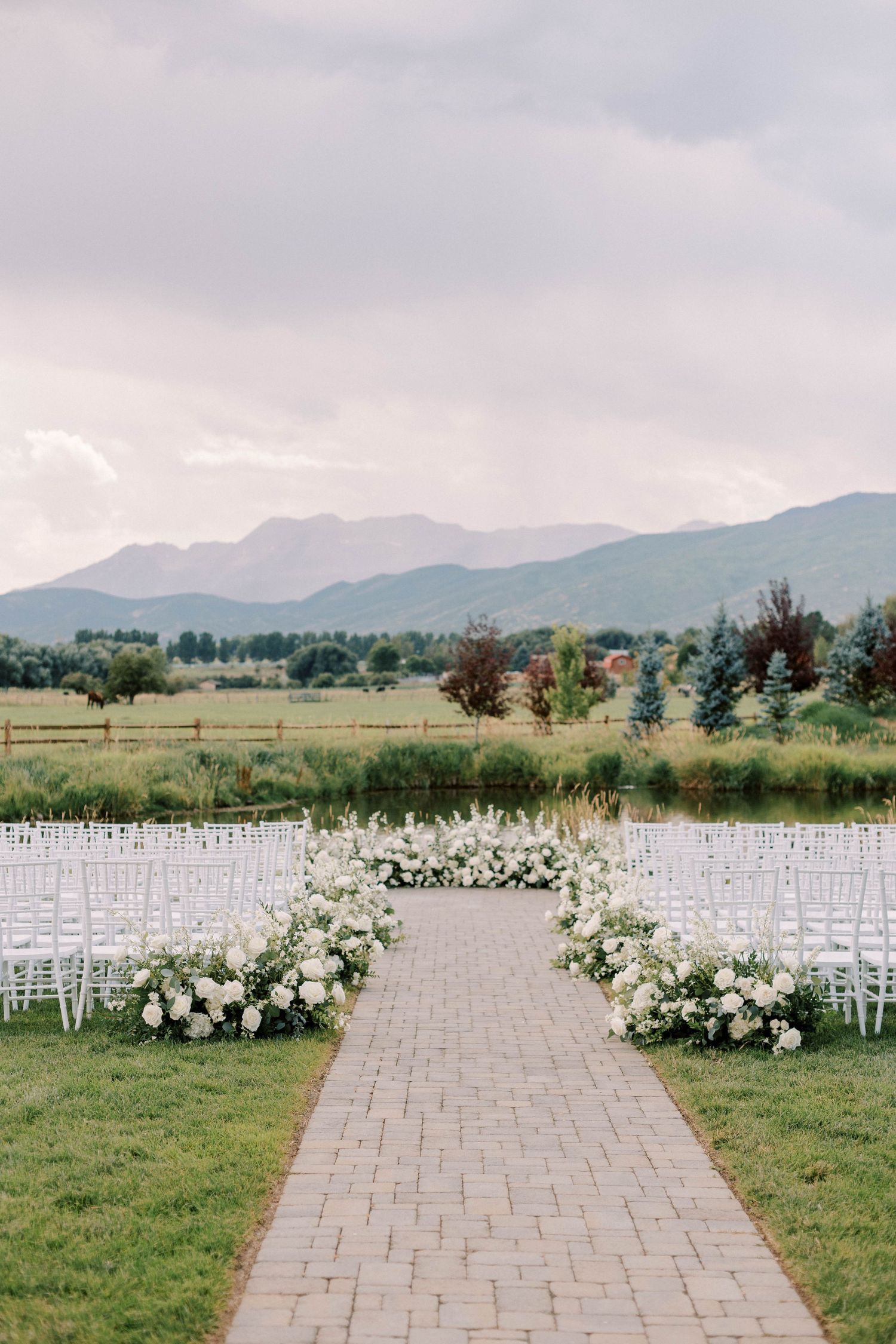 Stone pathway lined with white flowers leading to mountain view ceremony setup.