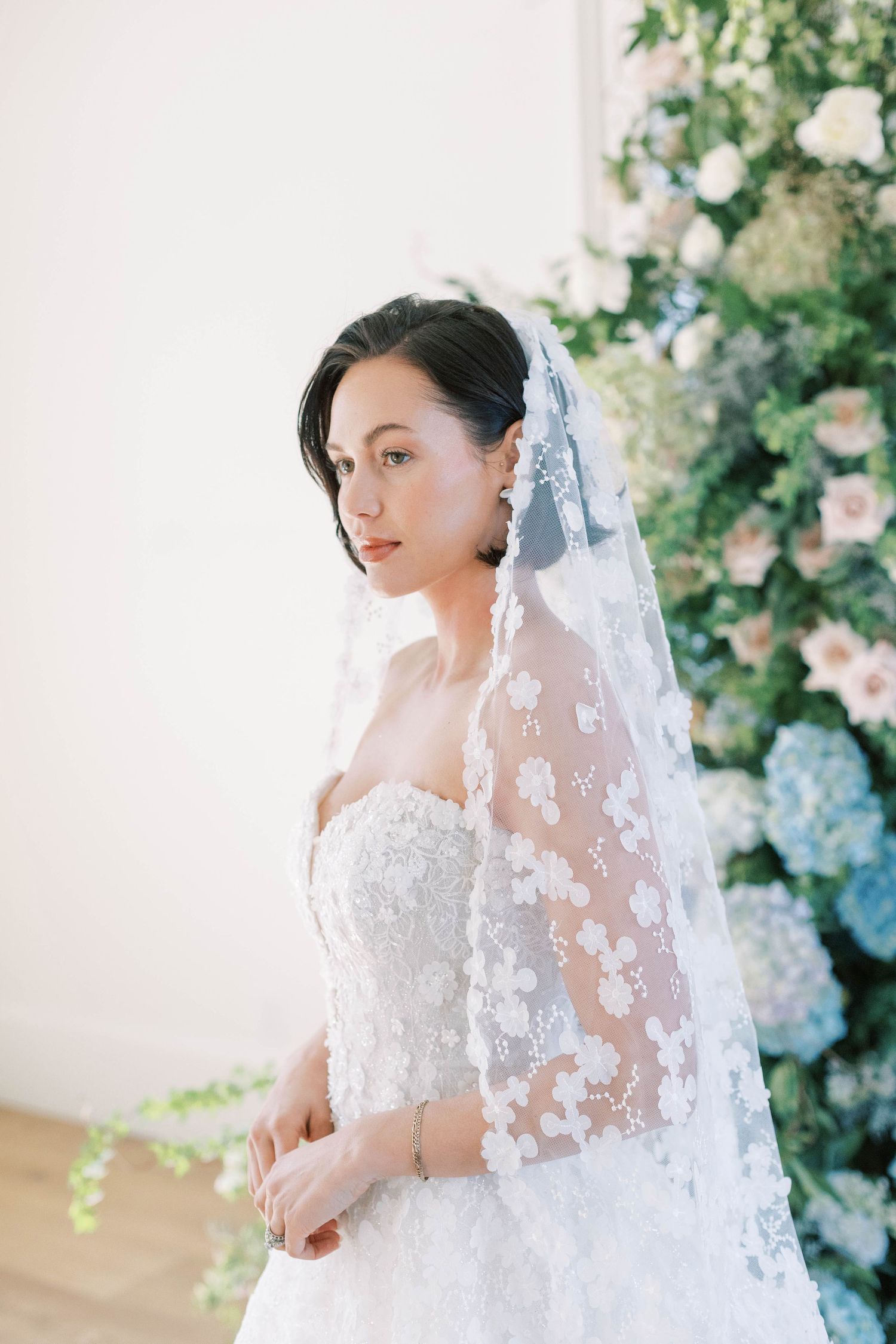 An ethereal bridal portrait featuring a detailed lace veil and strapless wedding gown.