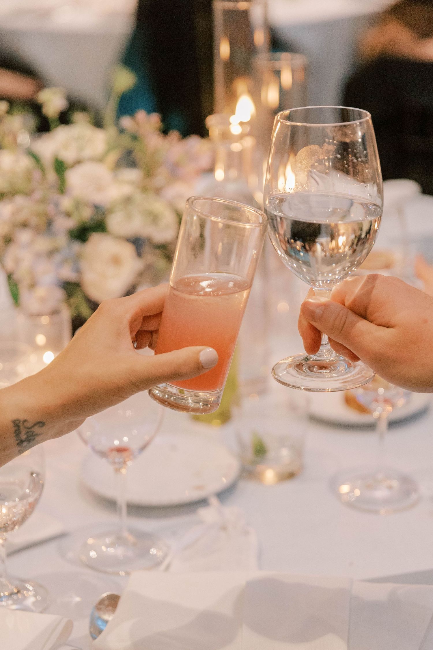 Close-up of hands toasting with champagne and wine glasses at elegant dinner setting.
