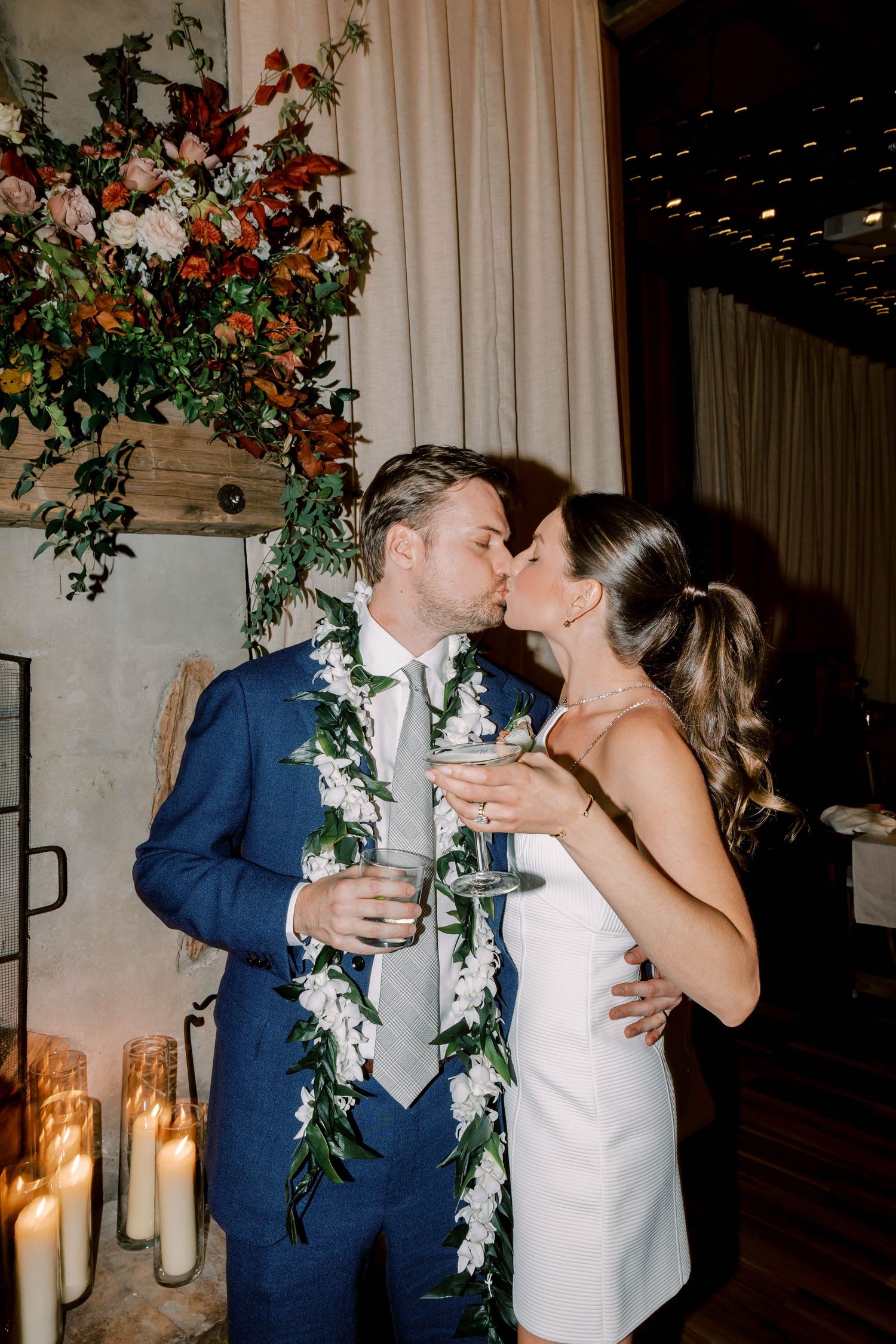 A romantic moment between newlyweds wearing floral garlands at their reception.