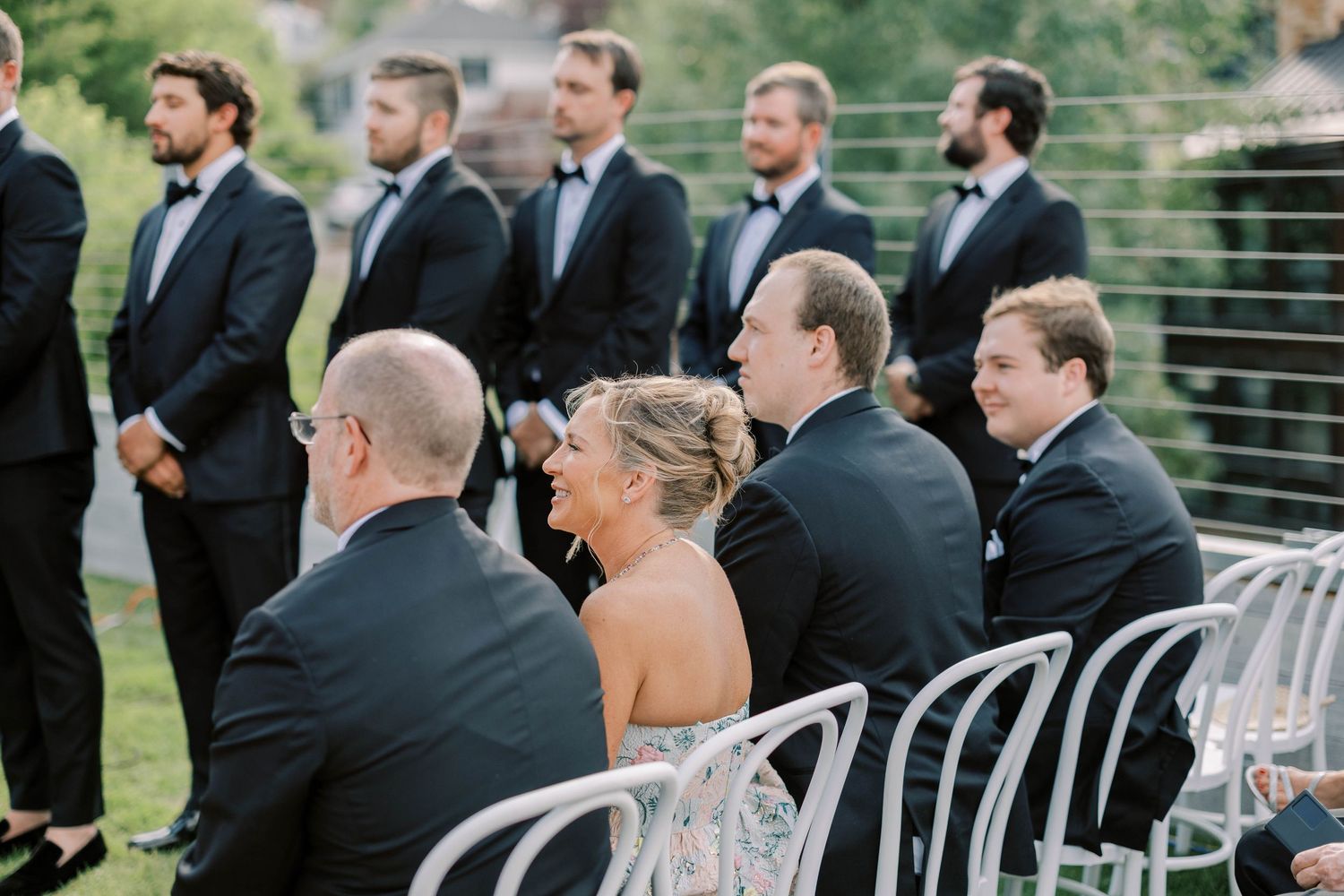 Wedding guests seated in white chairs at outdoor mountain ceremony.