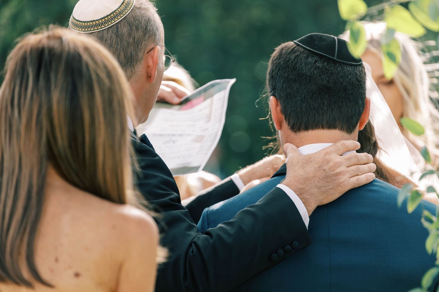 Jewish religious ceremony with participants wearing yarmulkes during an outdoor wedding service.