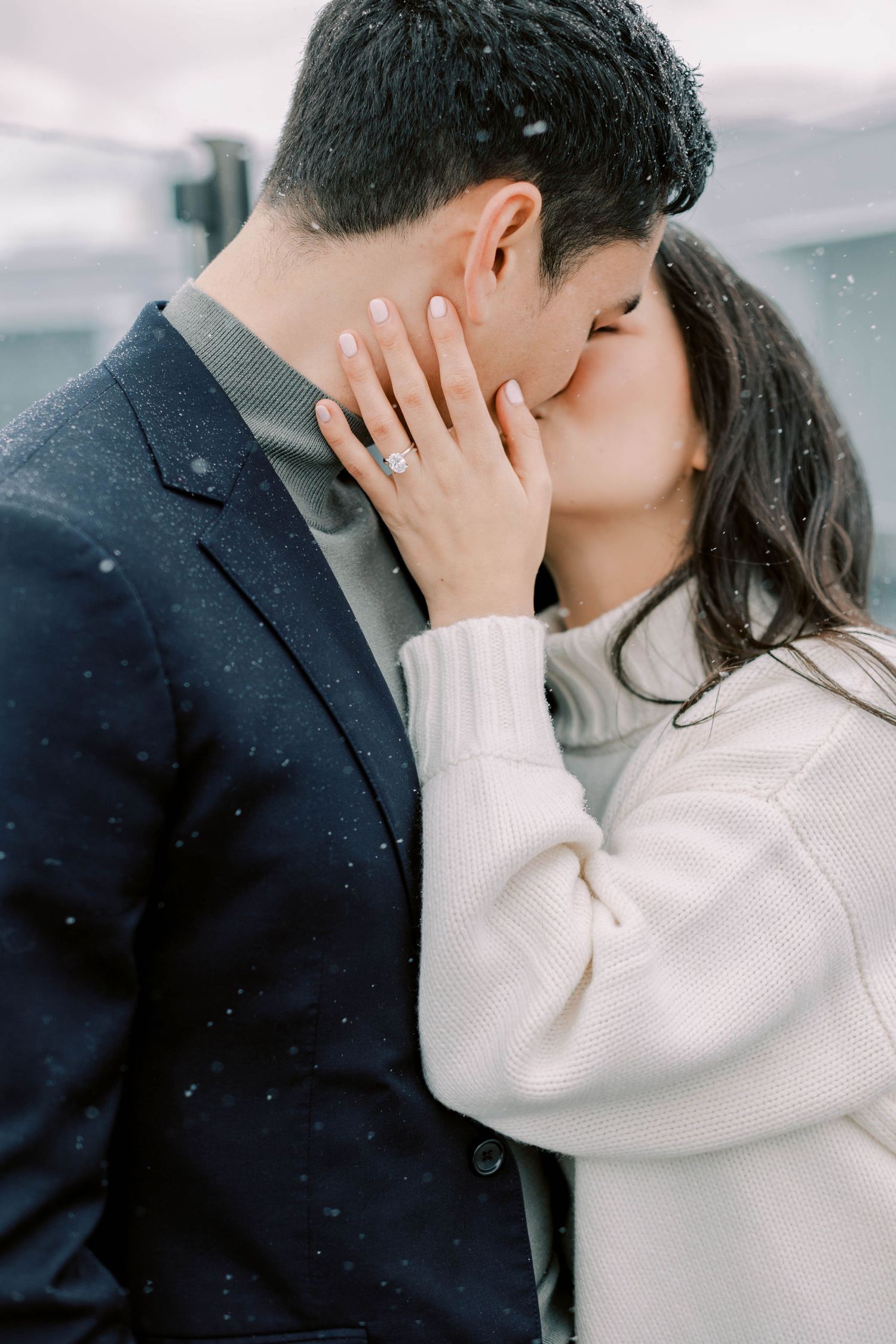 A romantic winter moment captured with soft snowfall and intimate embrace.
