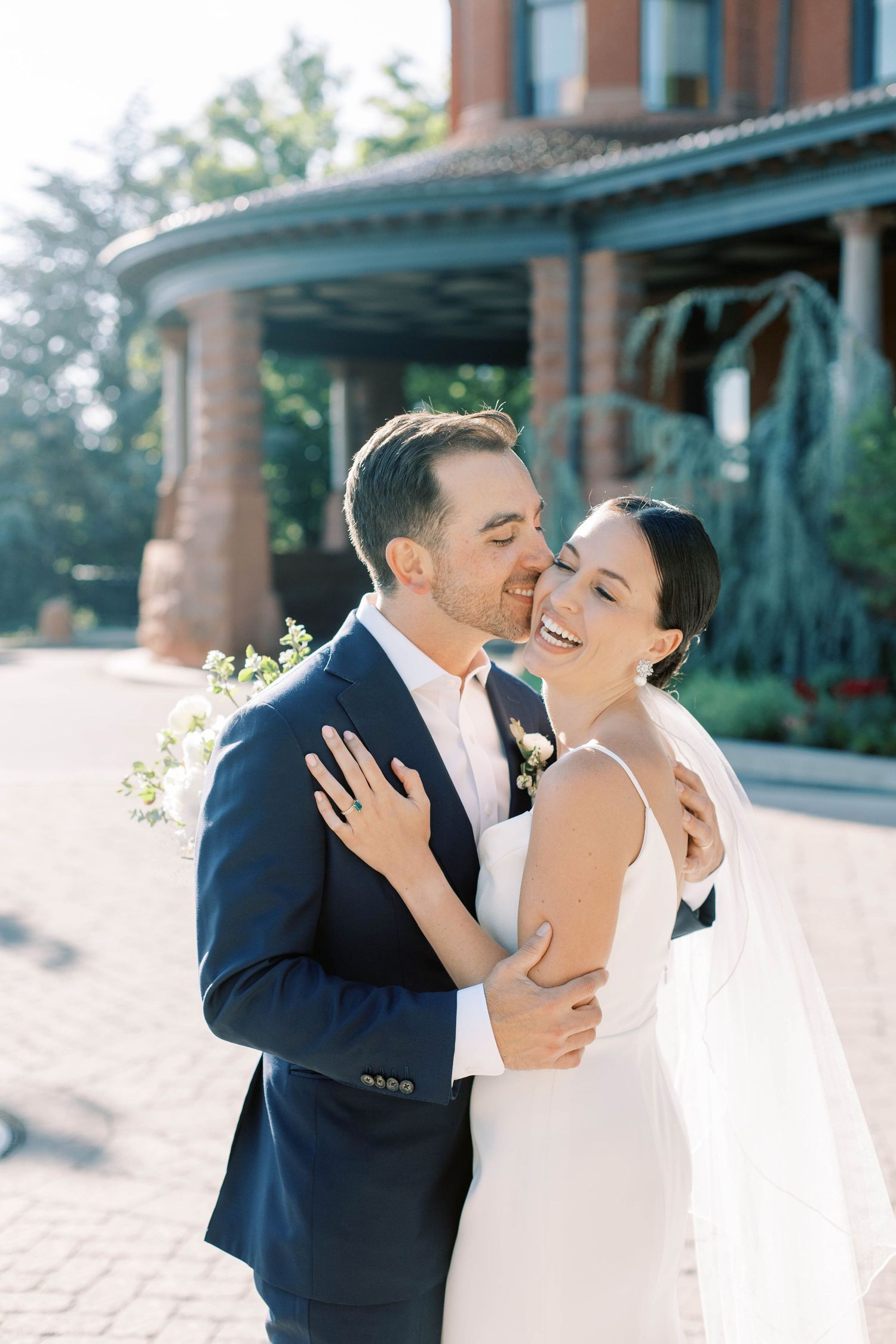 Romantic moment captured between couple in wedding attire outside a grand building with columns.