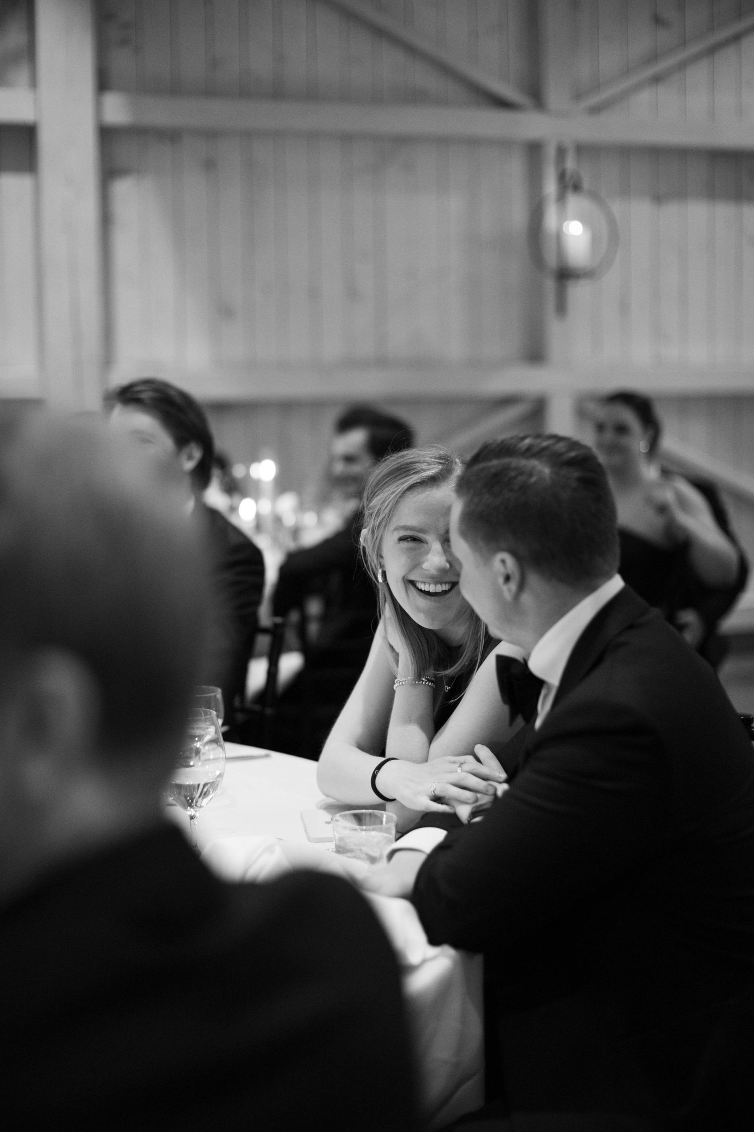 Intimate black and white photo of guests sharing a joyful moment at wedding reception.
