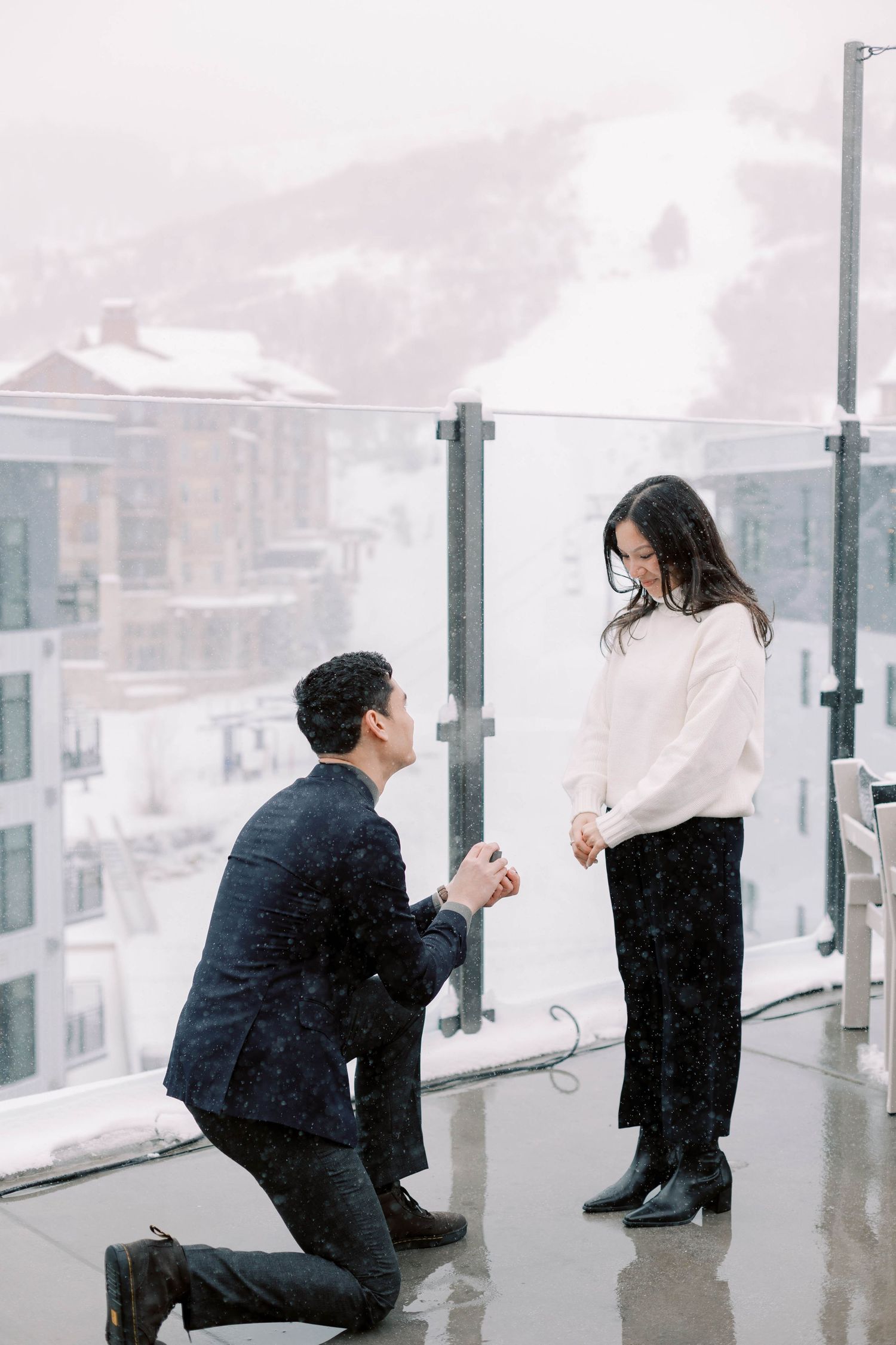 A proposal moment captured on a snowy rooftop terrace with mountain views at the pendry park city.