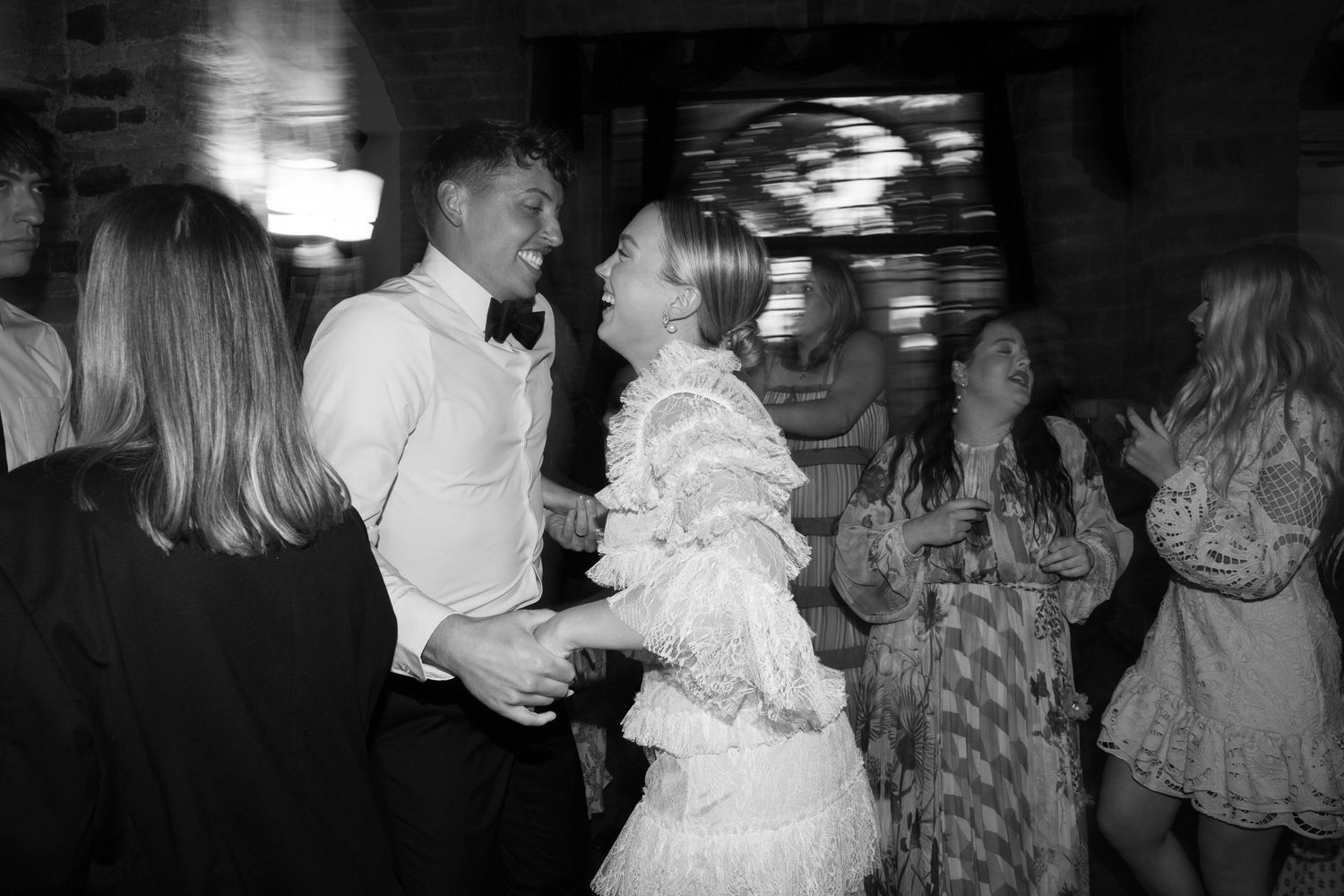 Black and white photo of guests dancing energetically at a formal event.